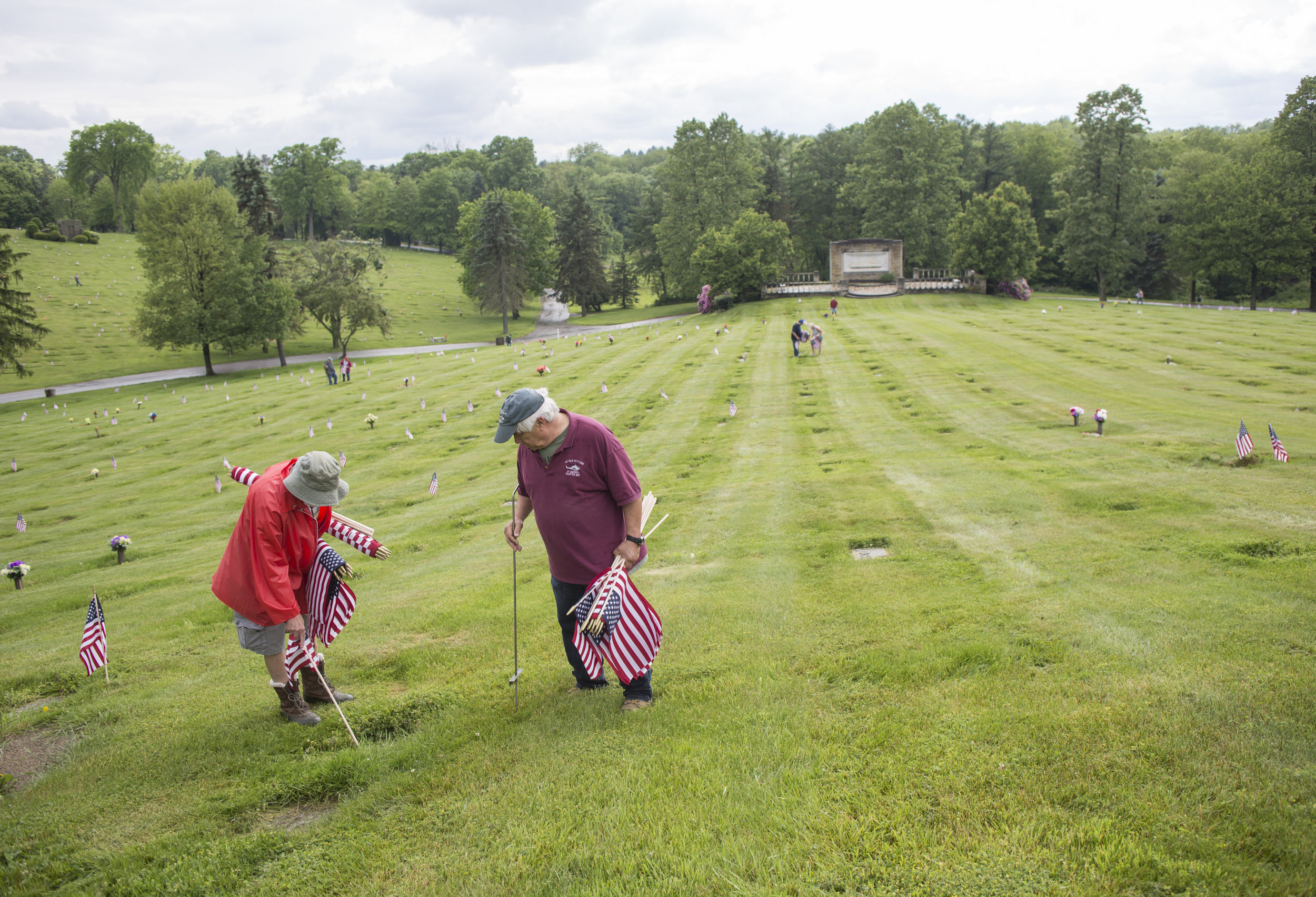  Dave Kane, left, of Patterson, and Larry Googins, of Baden, both members of the Vietnam Veterans of America Chapter 862, the largest VVA chapter in Pennsylvania, place flags on veterans' graves with other members of the VVA and VFW on Thursday at Sy