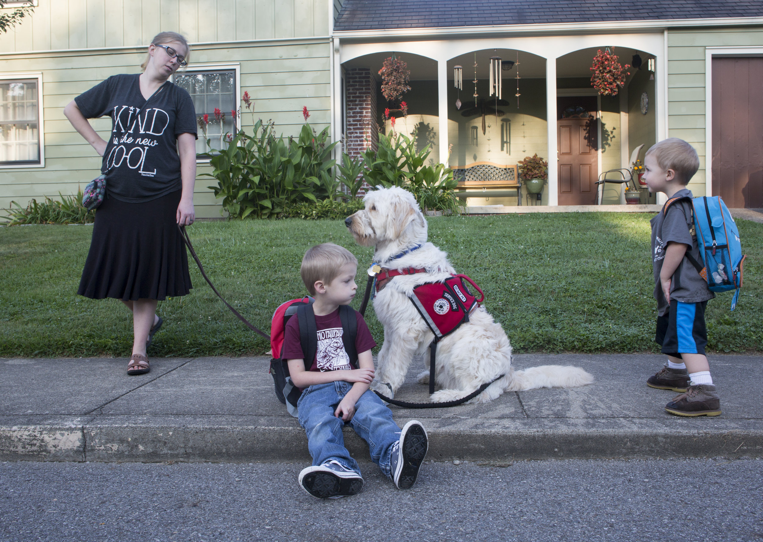  Josiah, middle, and Spad stop and sit on the sidewalk during their  morning walk to school while Josiah's mom, Rachel, and three-year-old  brother, Judah, wait for them to get up and continue walking. 