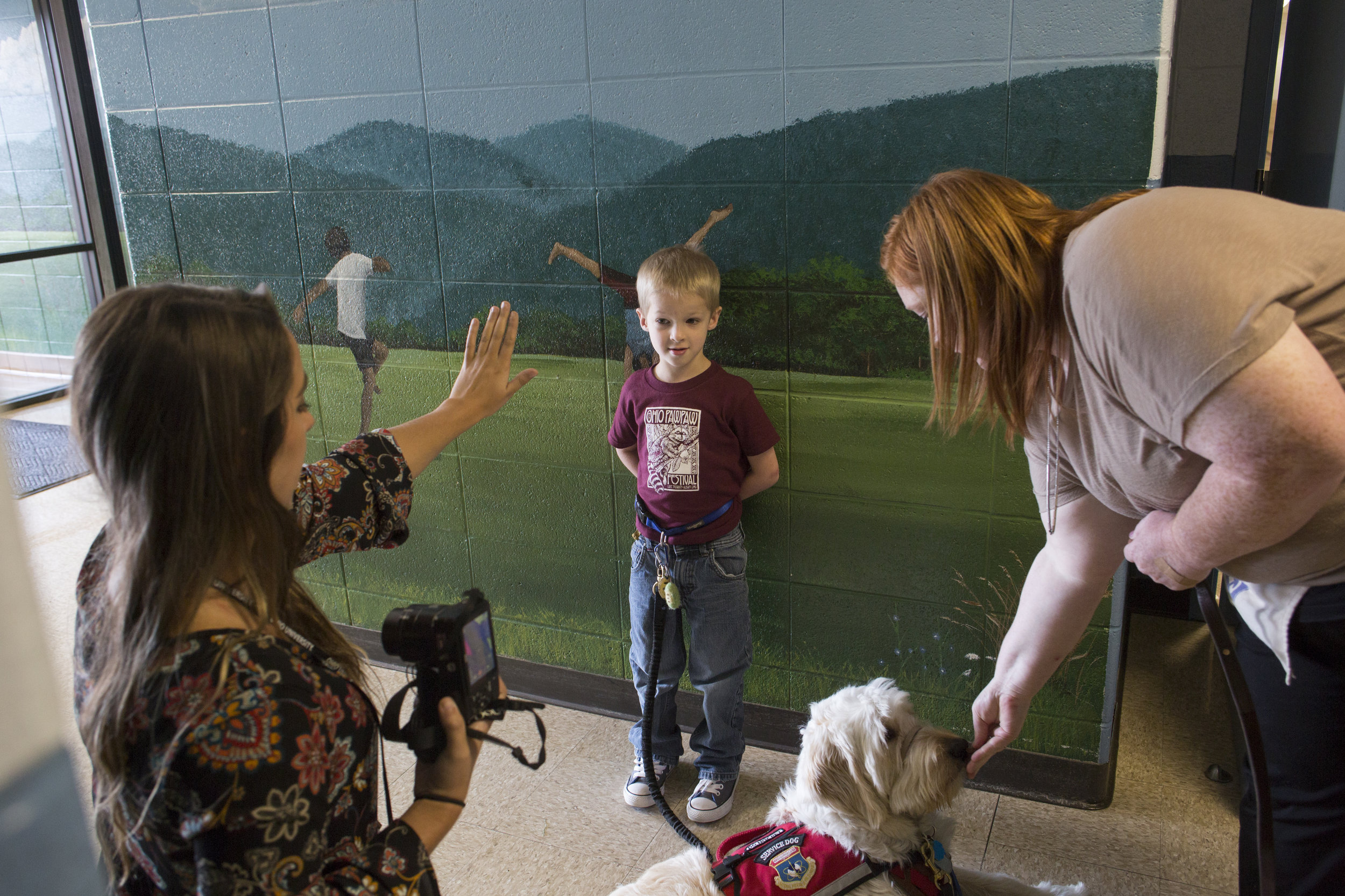  Kirsten Hannah, a teacher candidate, left, offers Josiah a high  five while Rachael Hamill, his paraprofessional, offers Spad a treat after Josiah gets his photo taken at school. 