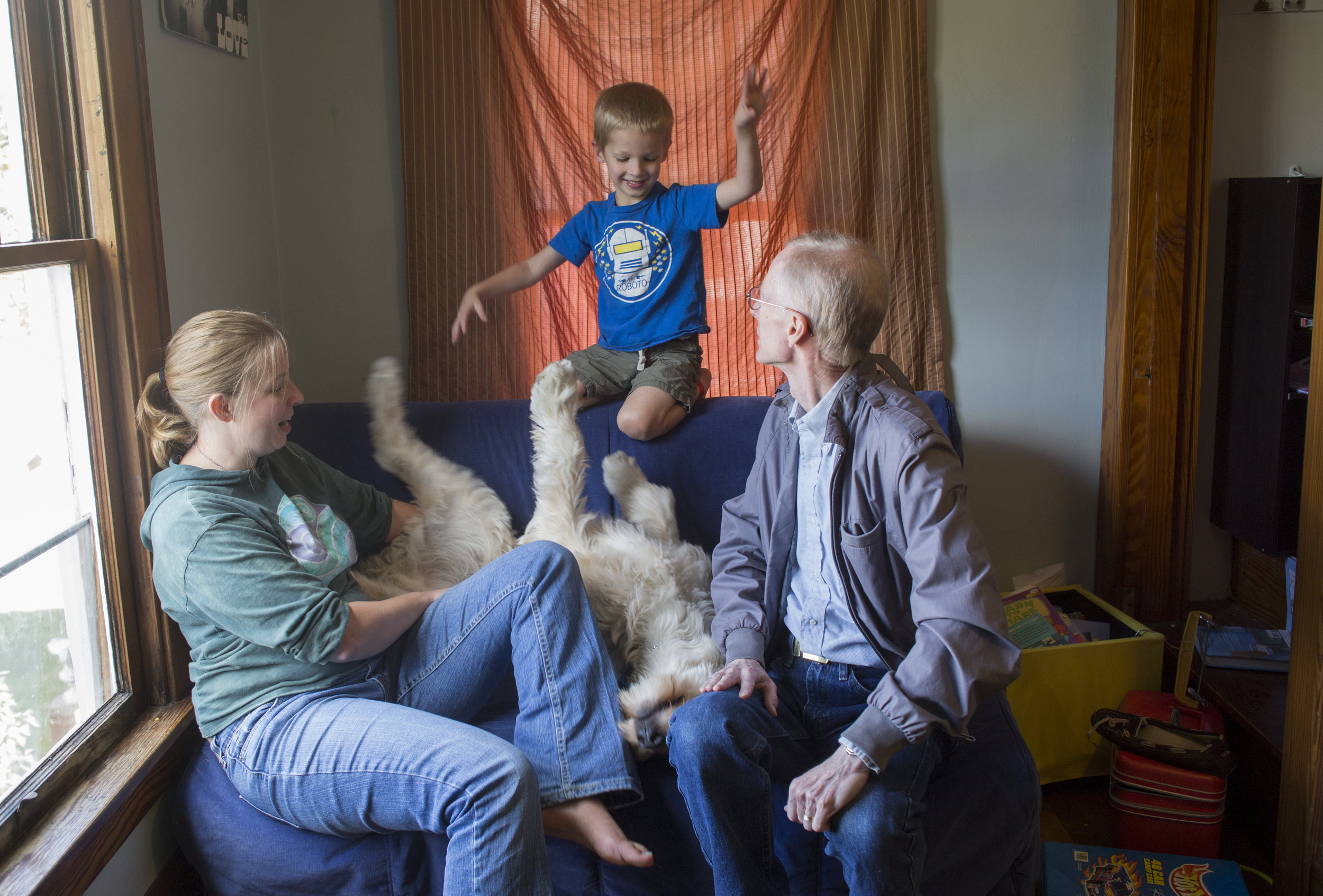  Josiah plays with Spad while his mother Rachel, left, and his  grandfather Bruce Metzger watch in the playroom of the Szostek house in Athens, Ohio. 