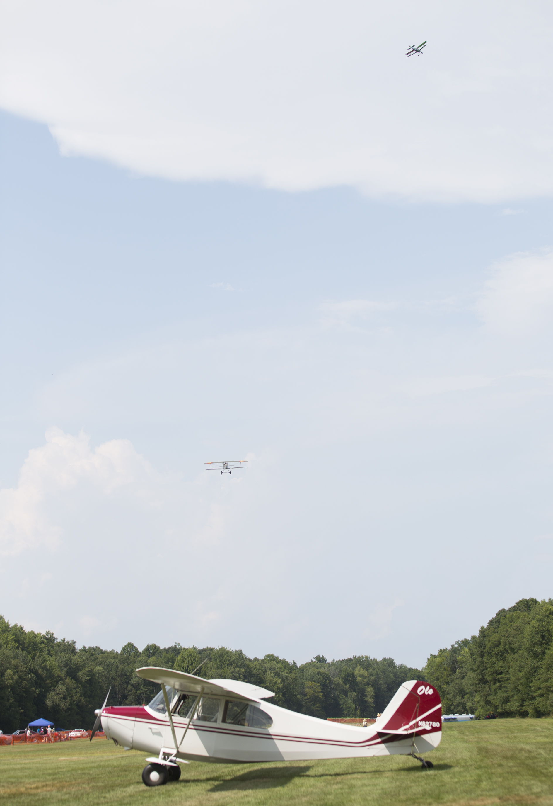  One plane remains stationary on the ground while two others fly above it at the 6th Annual Wings-n-Wheels at The Ernie Hall Aviation Museum in Warren, Ohio on Sunday, Aug. 5, 2018. 