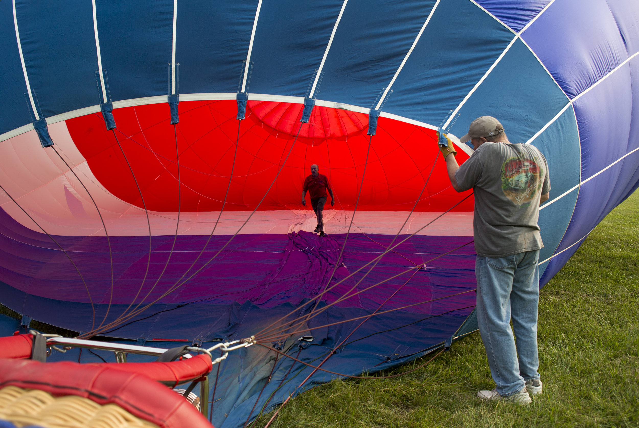  Rick Kohut, a hot air balloon pilot from Columbus, Ohio, walks inside a hot air balloon while Chuck Evans, of Austintown, Ohio, holds it up as it inflates at the Hot Air Balloon Festival at Mastropietro Winery in Berlin Center, Ohio on Sunday, Aug. 