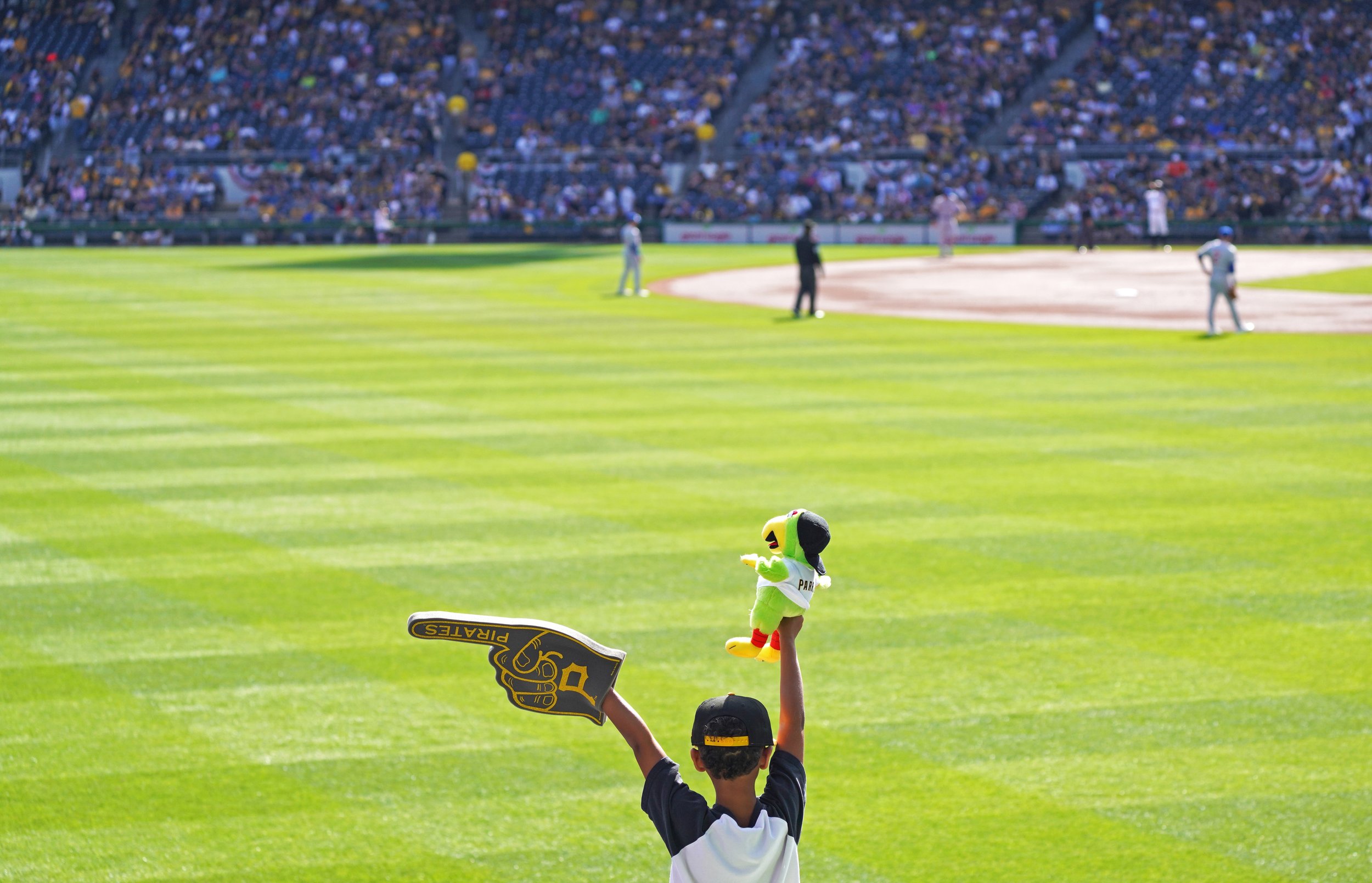  A young fan holds up a foam finger and a Pirate Parrot plush toy during the Pirates’ home opener against the Cubs on Tuesday, April 12, 2022, at PNC Park on Pittsburgh’s North Shore.  (Emily Matthews/Post-Gazette)  