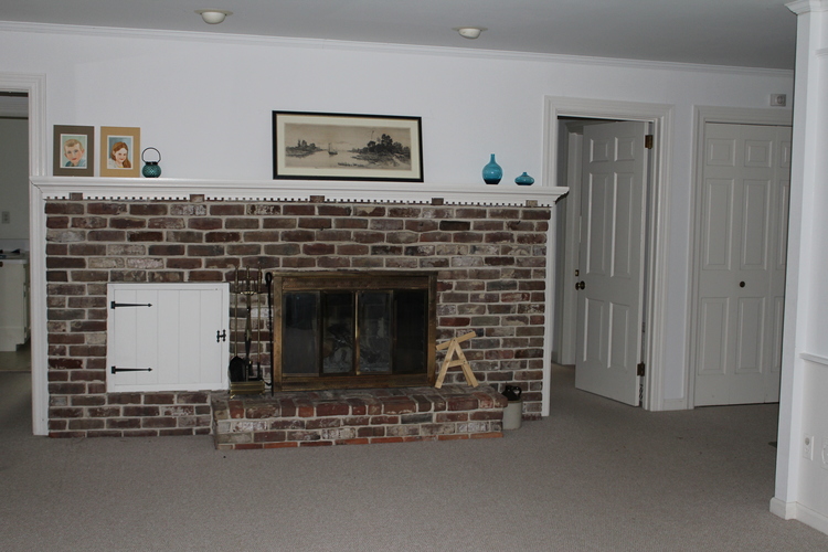 The fireplace sits between two bedroom hallways, and just beyond the main entrance hall