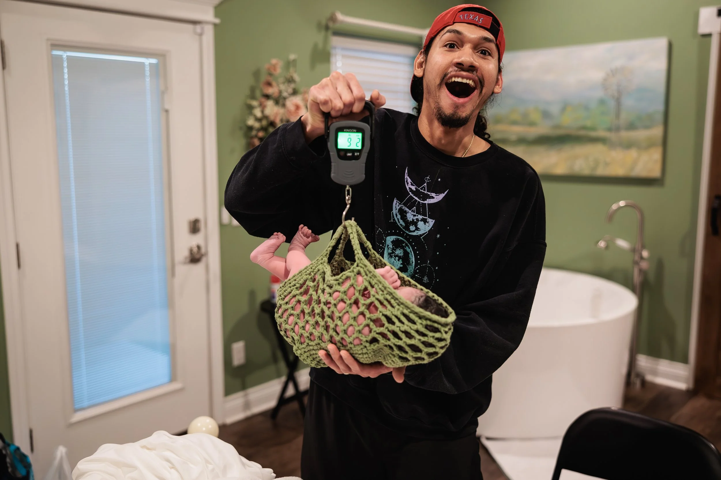 A new dad weighing his new baby, and is showing his surprised and excited expression of the weight of his new baby.