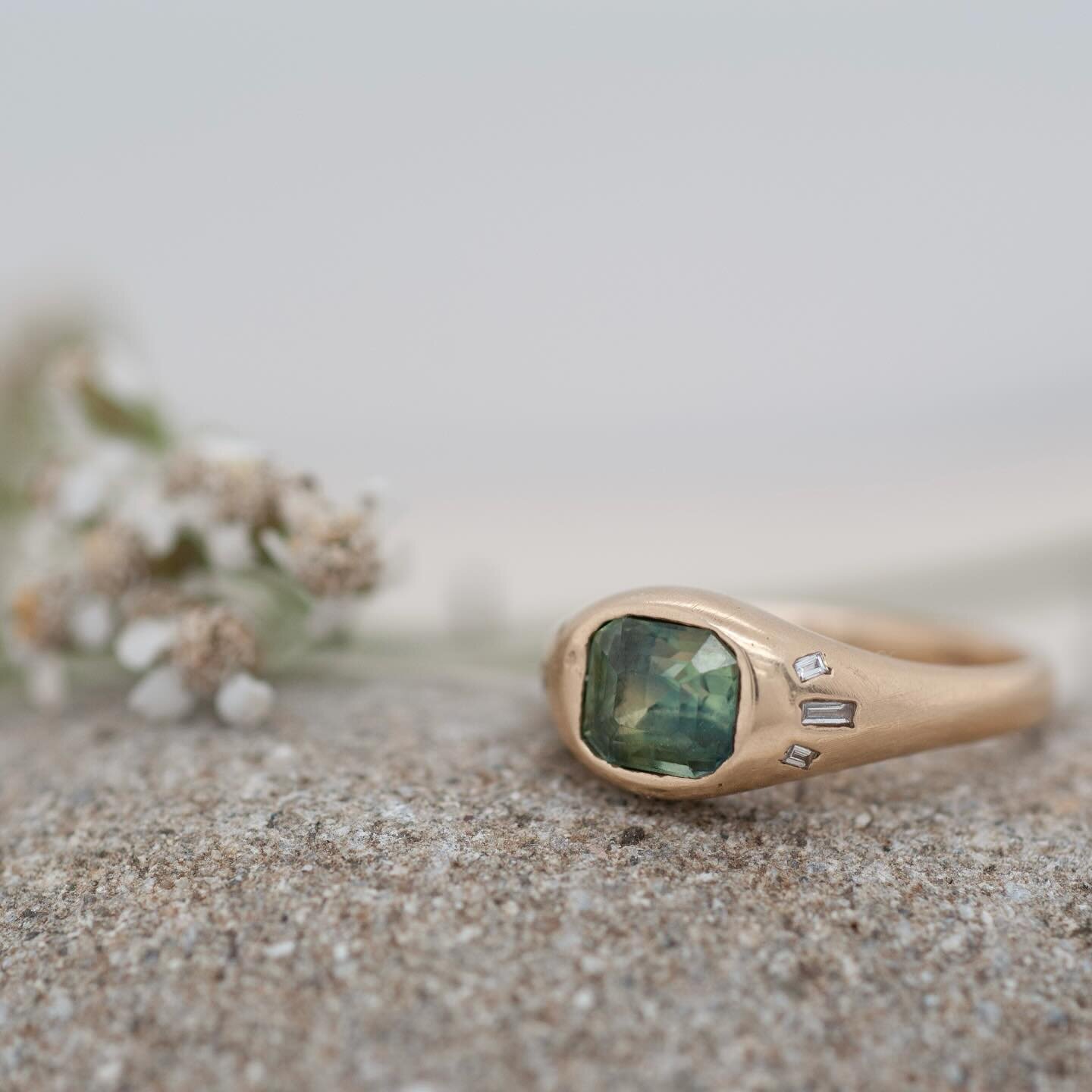 the ria ring. teal-hued sapphire with white diamond baguettes in a satin finish yellow gold. currently available in a size 6.75 and can be resized.