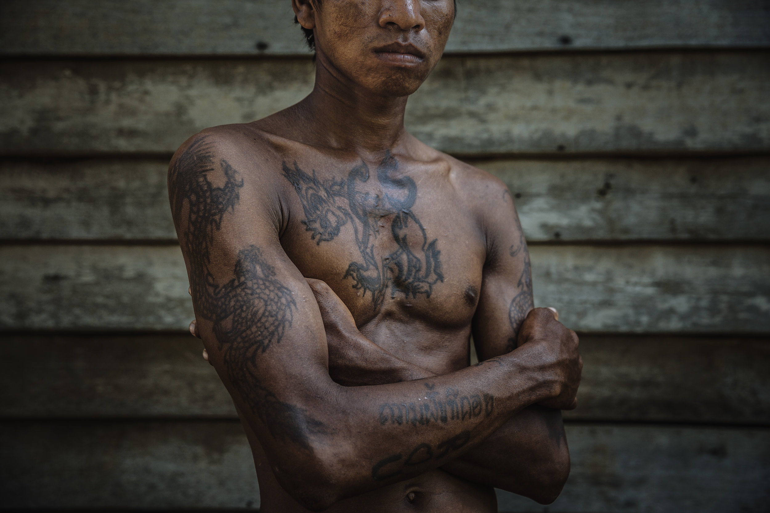 Ru is a former Cambodian fisherman. Originally from a small town near Siem Reap, he and a number of other men ventured into Thailand looking for work and were eventually trafficking onto fishing boats where they were forced to work for over six years as slaves. He has a number of tattoos, many of which he does not full understand their meaning. The tattoo on his chest is inspired by a similar design that one of his captors, the ship captain, had which he liked. Tattooing is an ancient part of Khmer culture. Magical tattoos, known as sok ya, are believed to protect the wearer from anything from bad luck to physical harm.