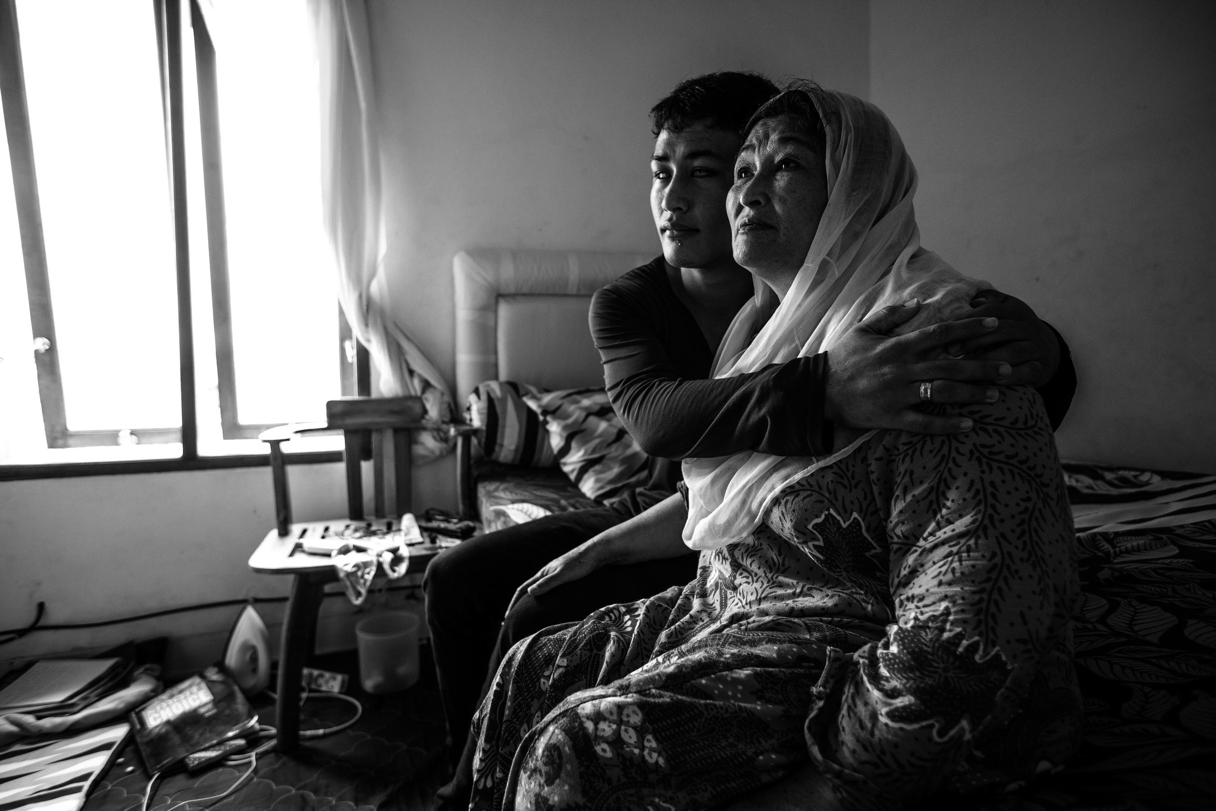 Bilal hugs his mother Nikbath in their small home in Makassar, Indonesia. Refugees from Afghanistan, they fled their village when the Taliban killed this father because they were from the Hazaras, an ethnic minority which is often discriminated upon and not viewed as true Afghans in the eyes of the Taliban. Bilal has suffered from blindness since he was born. His blindness is curable through a commonly medical procedure but they cannot afford it the treatment. Bilal hopes that one day he will be able to gain his sight and be able to read so that he can continue his education.