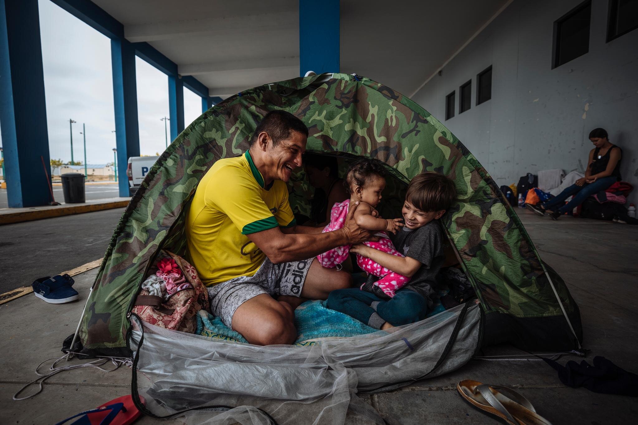Cesar plays with his daughter and nephew in a makeshift tent on the border between Ecuador and Peru. The former mechanic left the country with his family when his salary could no longer feed his family. The family reached the border a month ago. Th