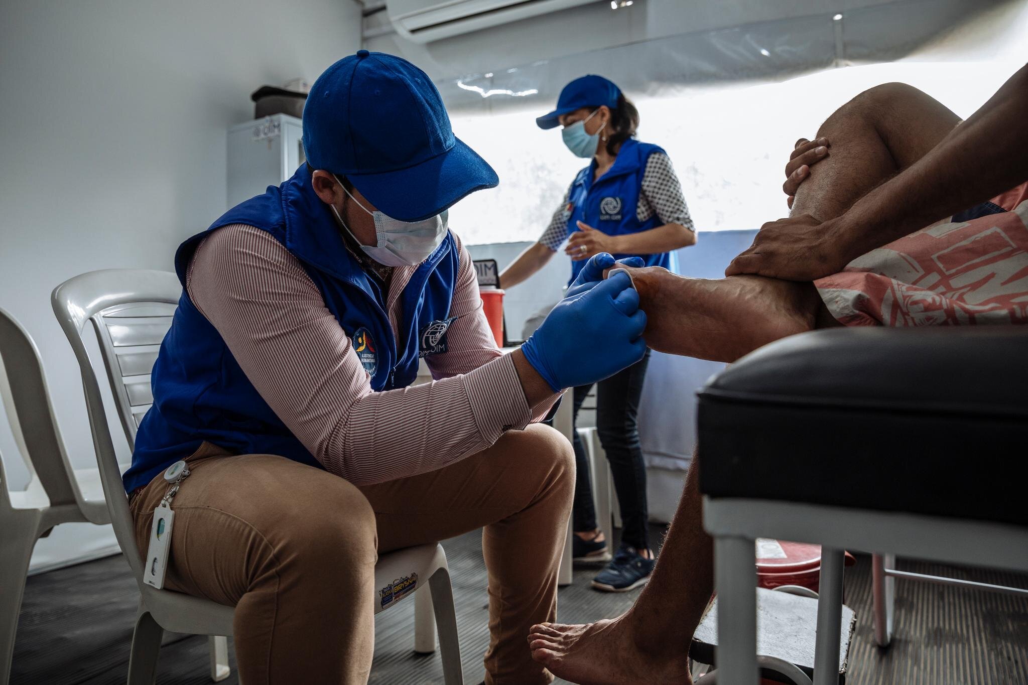 Caminantes have their injuries treated by aid workers at an International Organization for Migration Humanitarian Tent along the road to Pamplona, Colombia. Their long journeys, often made in flip flops or sneakers, result in many foot injuries.
