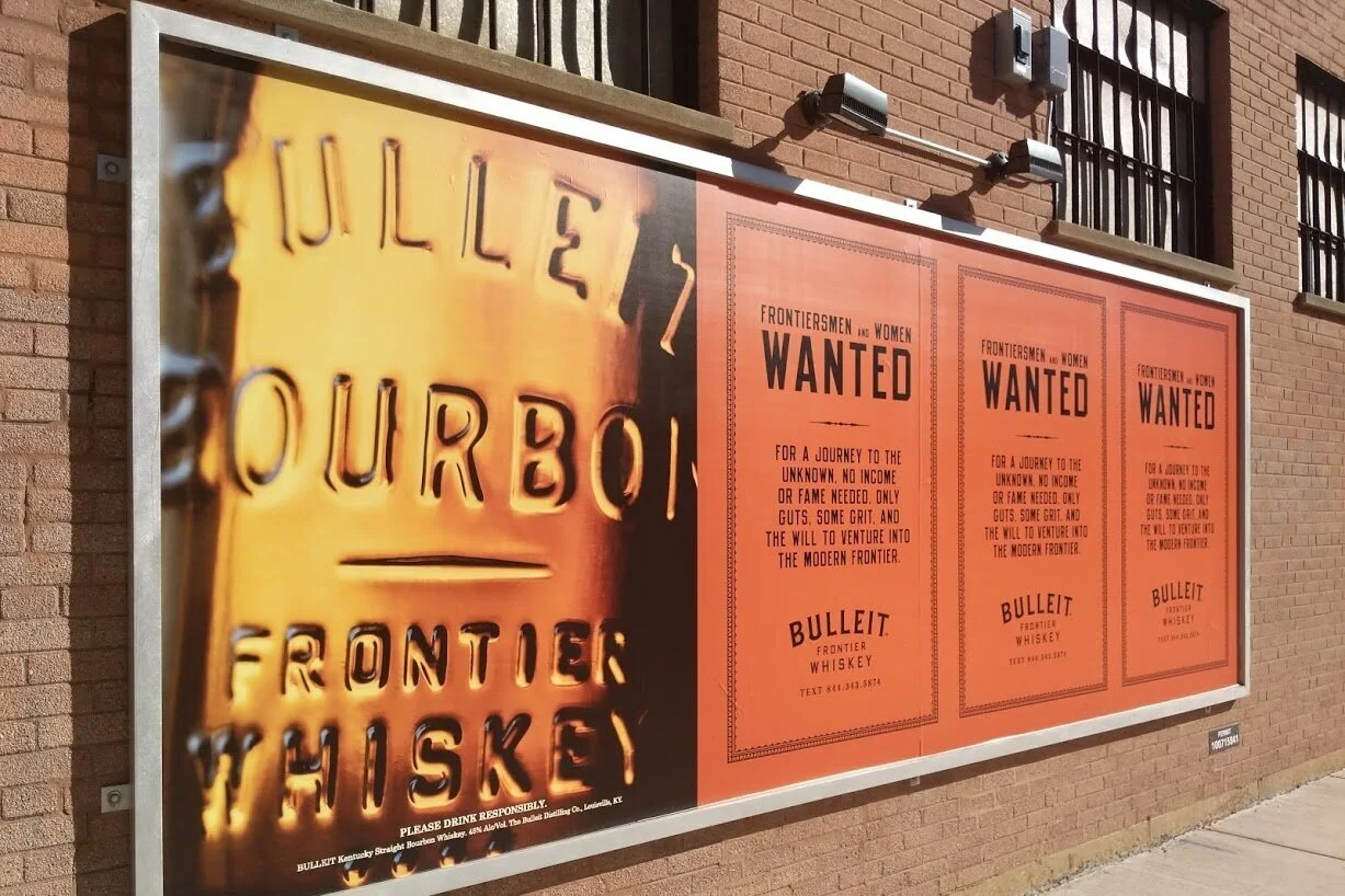 Bulleit Bourbon wild posting ad on a Chicago brick wall reaching pedestrians in a busy urban neighborhood
