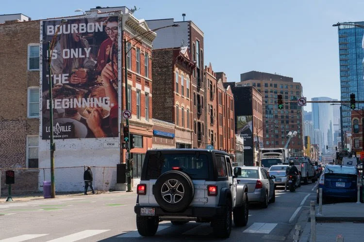 Traditional wallscape billboard advertising in a busy urban corridor showing large-format OOH visibility for drivers