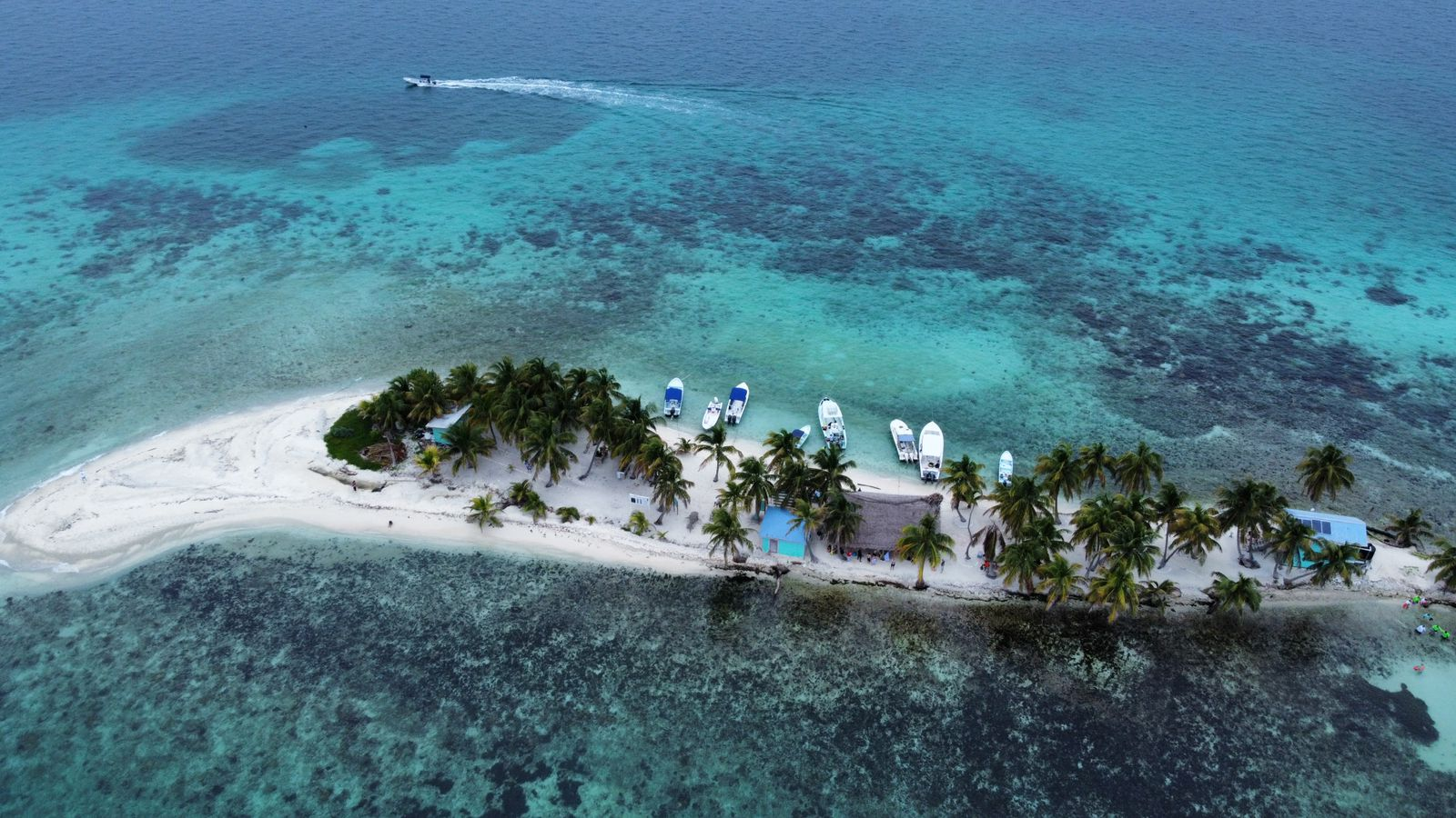 An aerial photograph of Laughing Bird Caye National Park, showing the sands with a motorboat in the distance