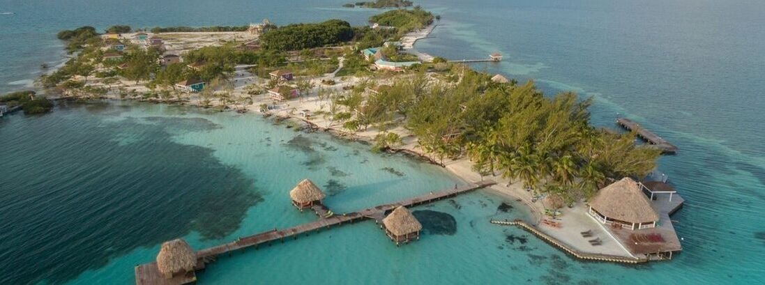 An aerial view of Coco Plum Island Resort, showing all the buildings, trees, and surrounding ocean.