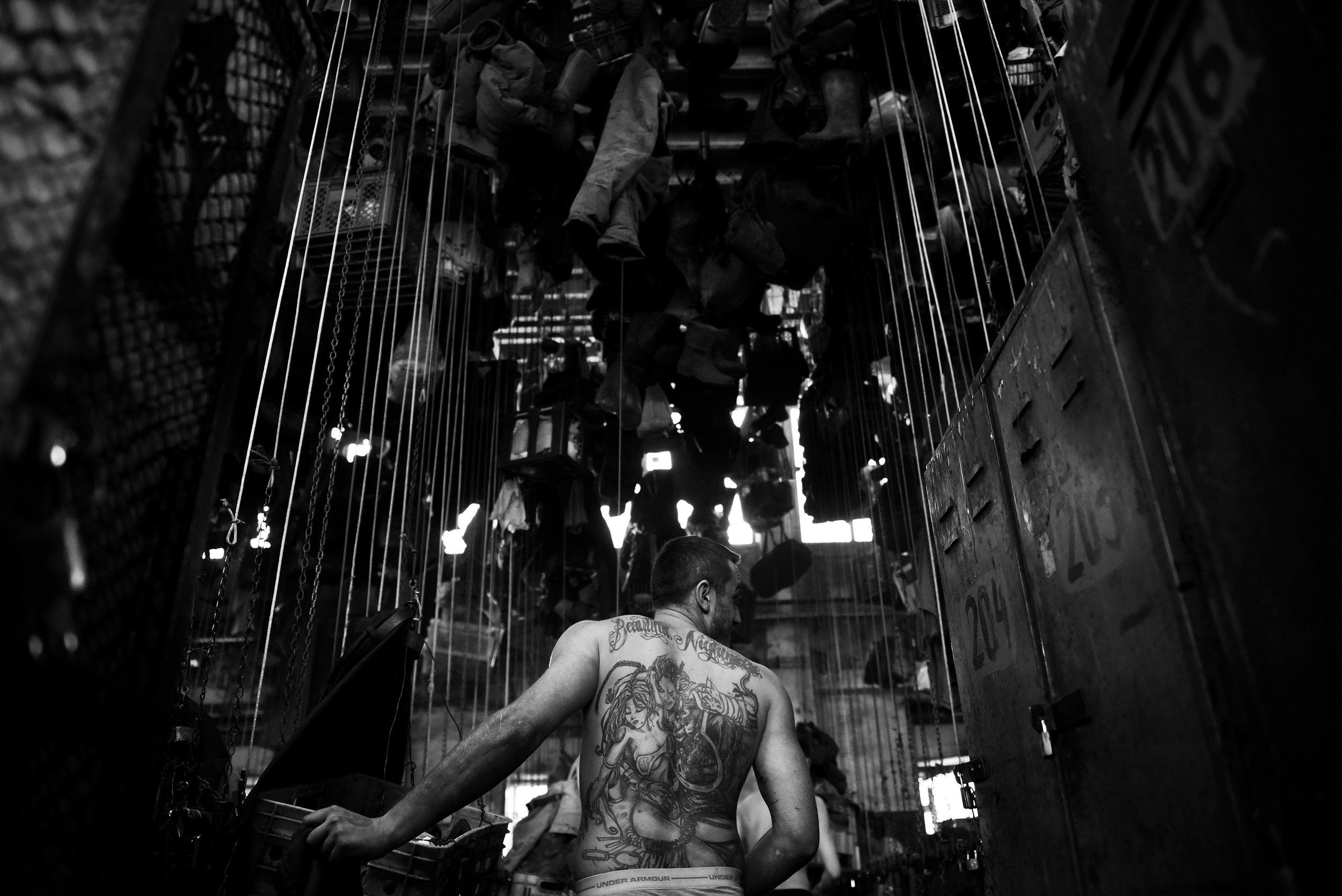  Coal miner takes off dirty clothes after work. Personal belongings are kept in baskets that are hooked to the chain with which they will raise it high and lock them. 