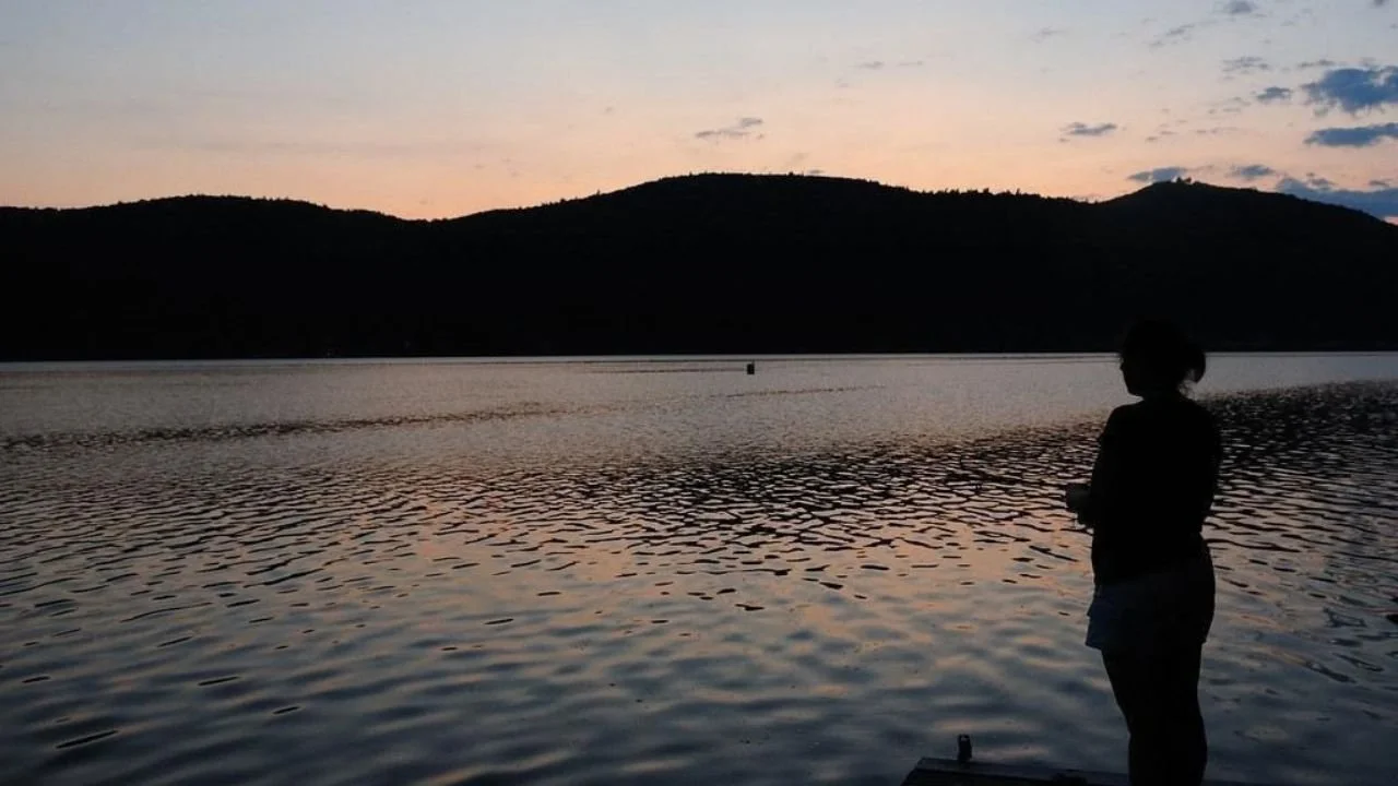 Woman fishing at sunset on Lake Champlain dock. 