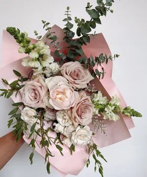 Wrapped bouquet featuring peach garden roses, ranunculus and spray