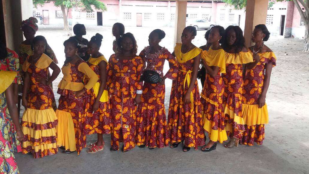 Ten young women celebrated their sewing success, lined up for a graduation procession in the dresses they made.
