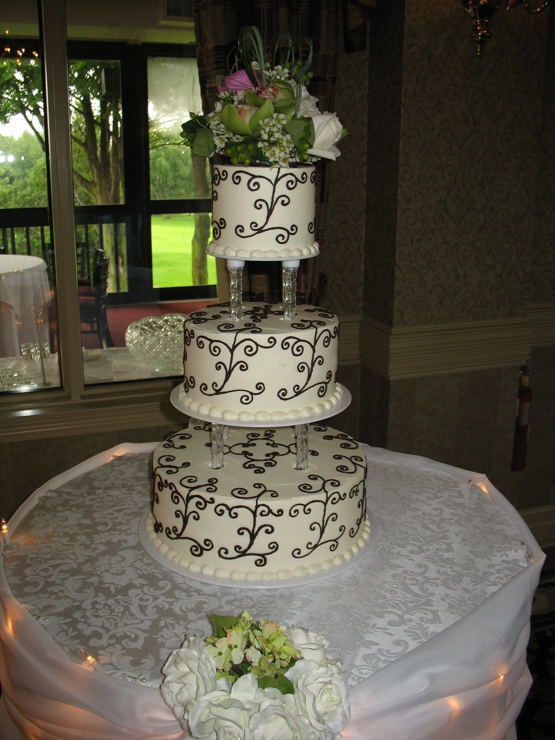  Ines and Robert chose a black scroll design and wanted some extra height to their cake. We separated the tiers using clear pillars and continued the scroll onto the top of each tier, which was a great way to avoid having it look barren in between th