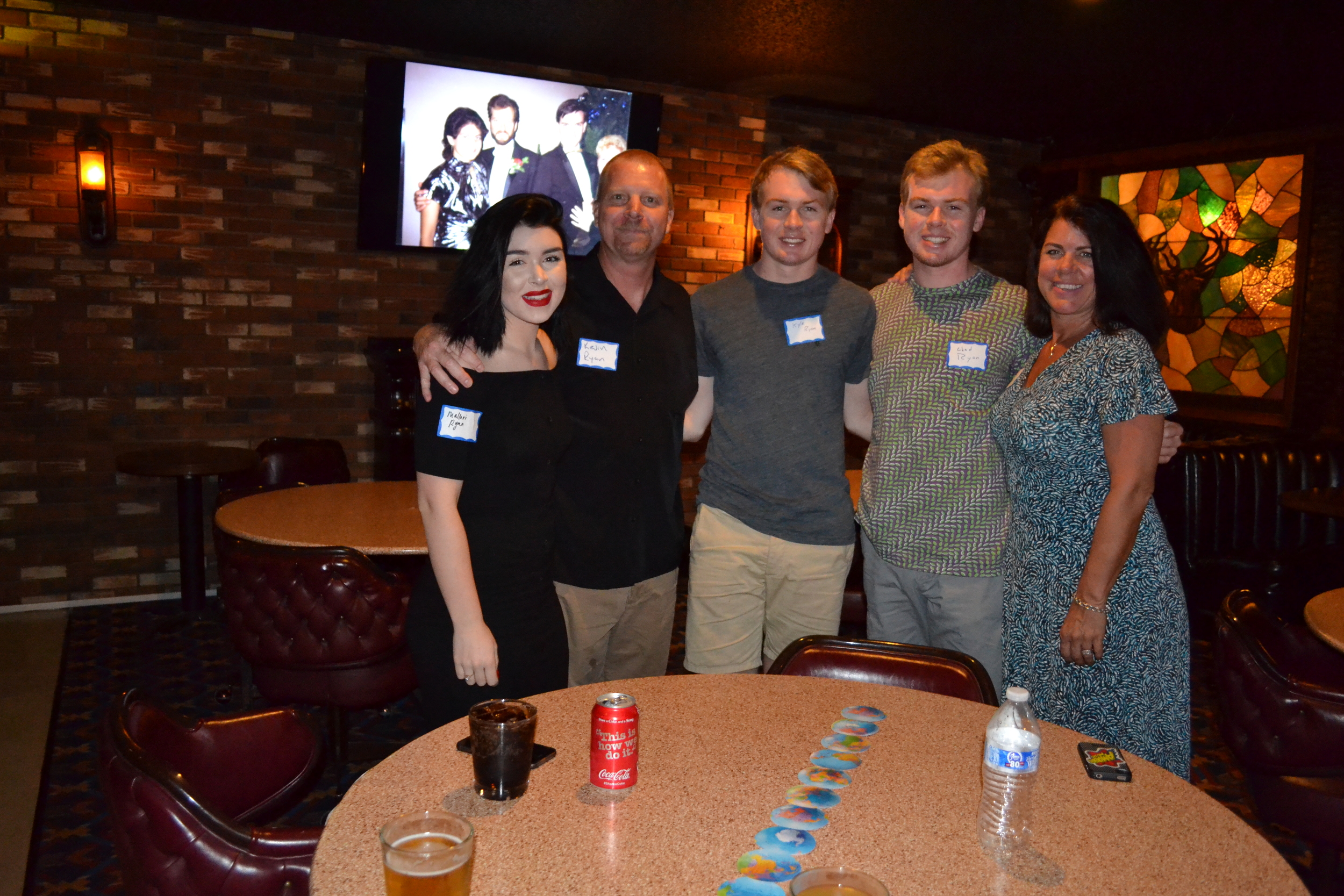Kevin Ryan (2nd from left) and his family posing for a photo, with a slideshow photo in the background