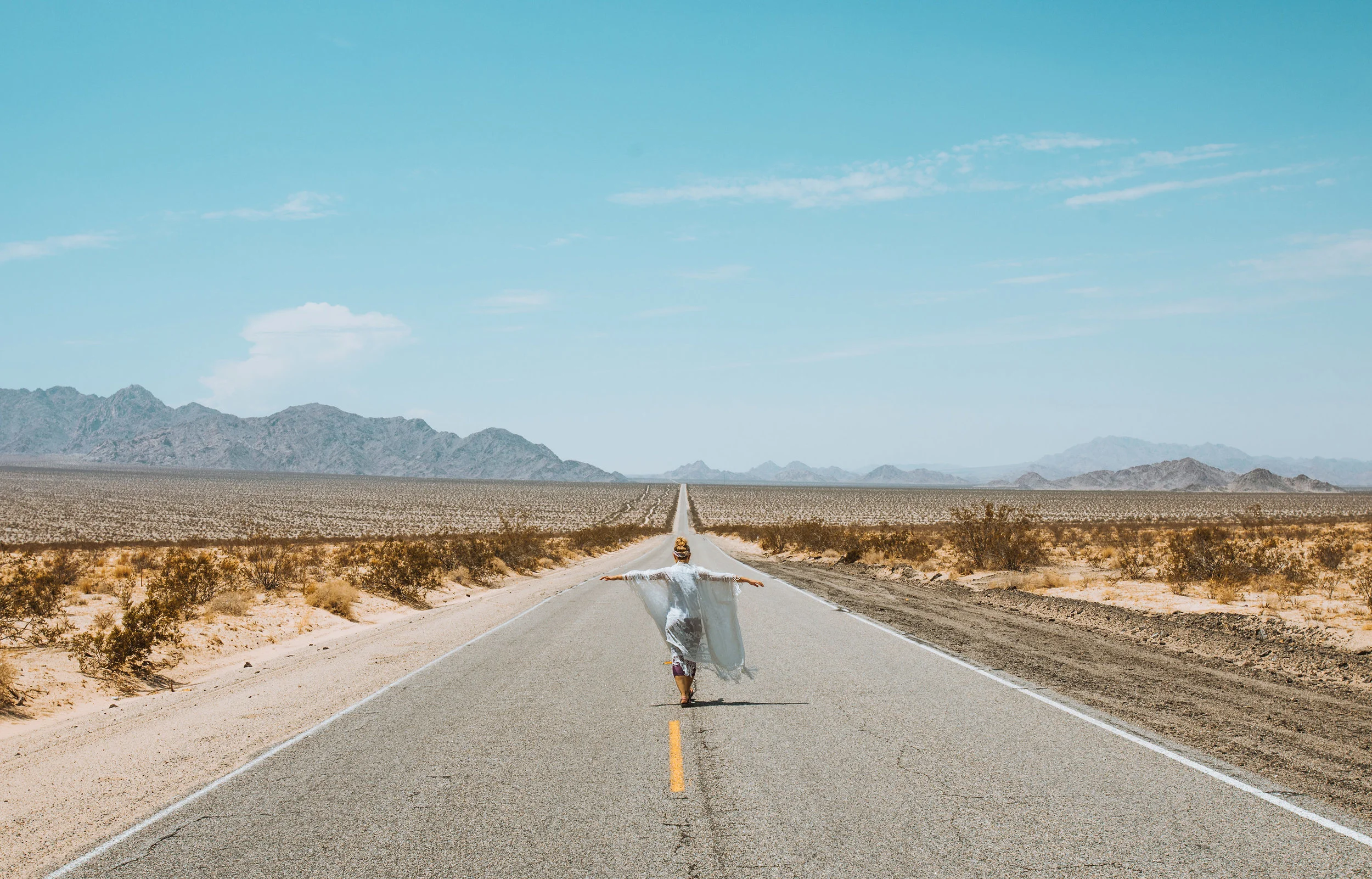 Millennial woman walking down open road out west