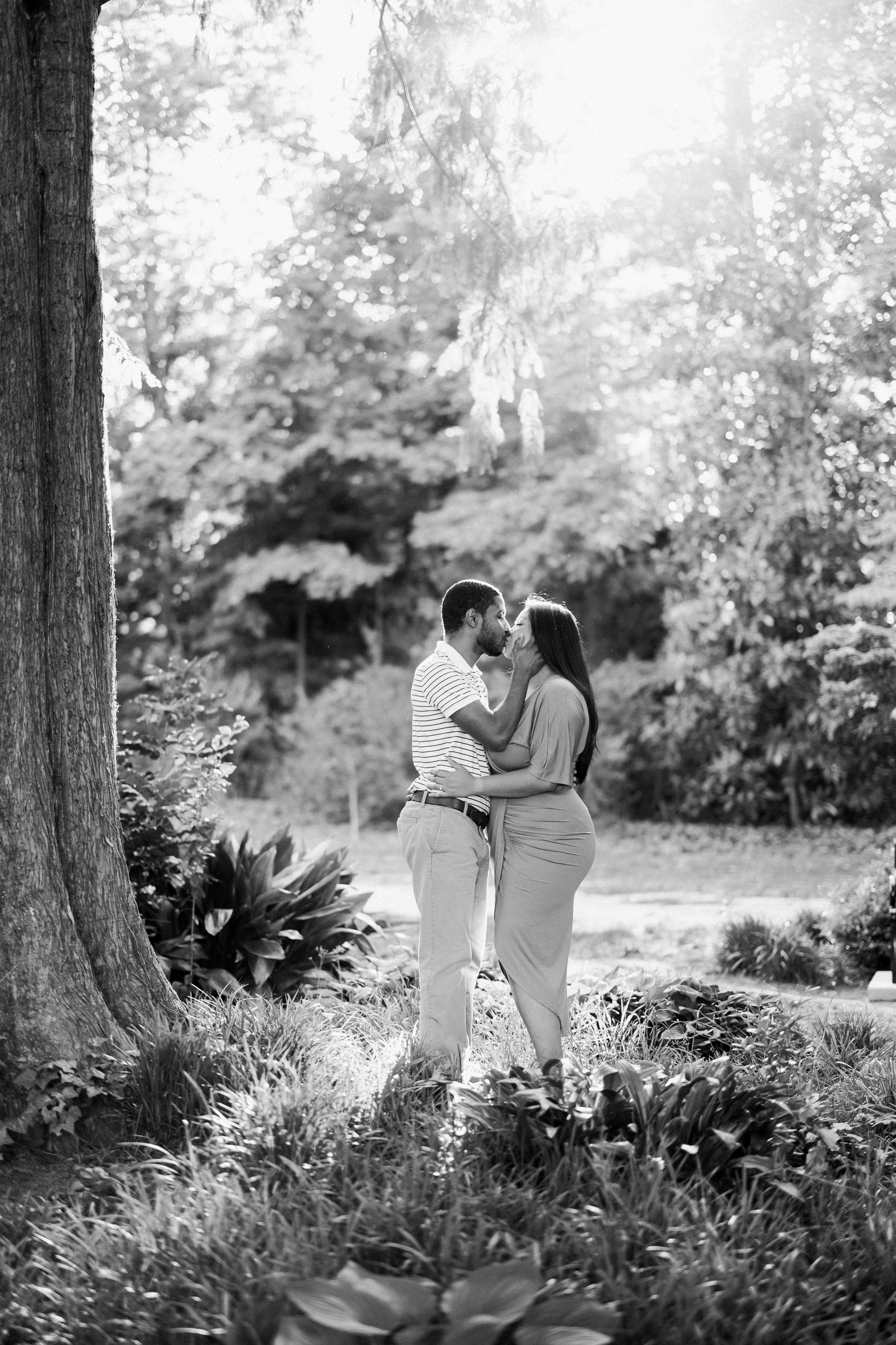 Black and White Image Couple Standing Under Tree Engagement Photos in The Raleigh Rose Garden Fancy This Photography