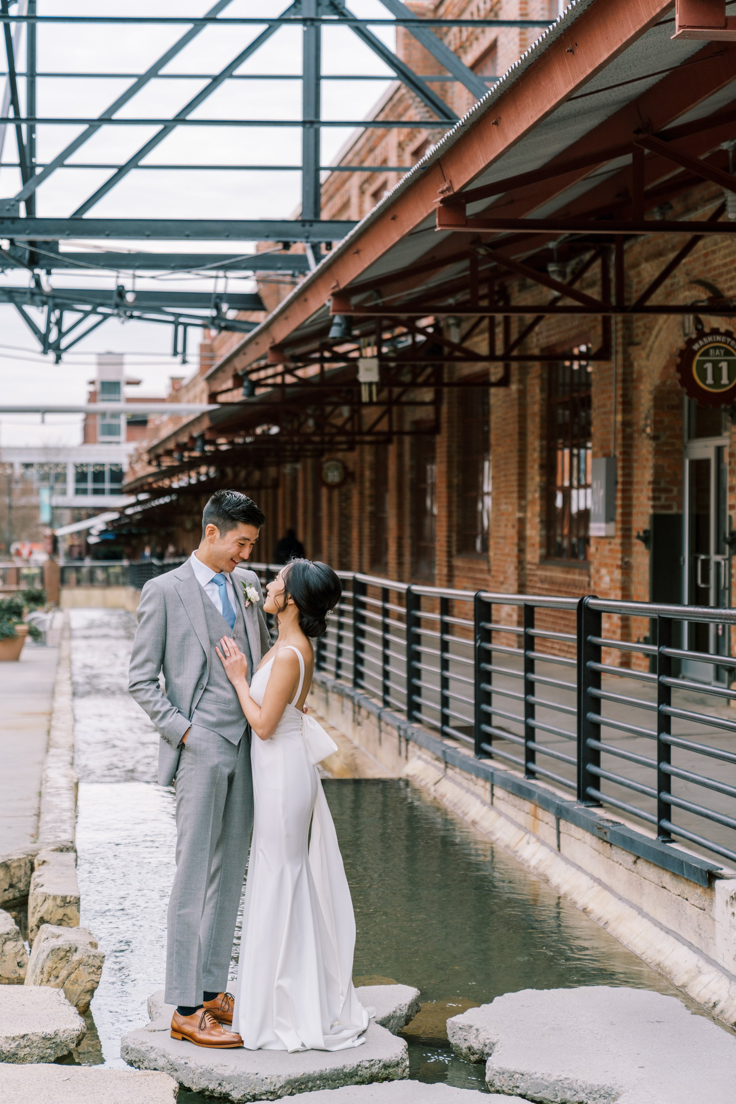 Bride and Groom Pose Over Water American Tobacco Campus Wedding at Bay 7 Durham NC Fancy This Photography