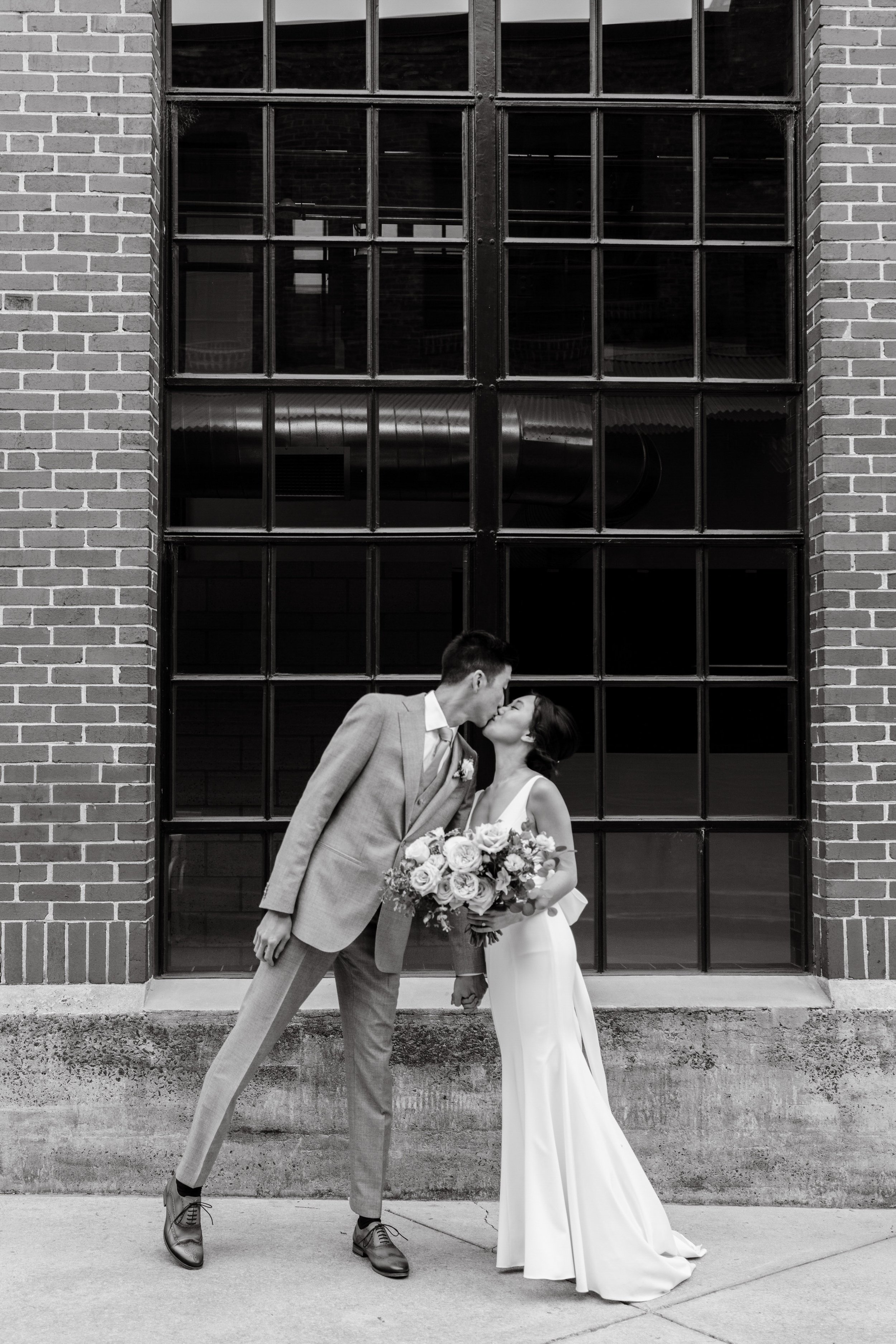 Black White Image of Bride and Groom Kiss American Tobacco Campus Wedding at Bay 7 Durham NC Fancy This Photography