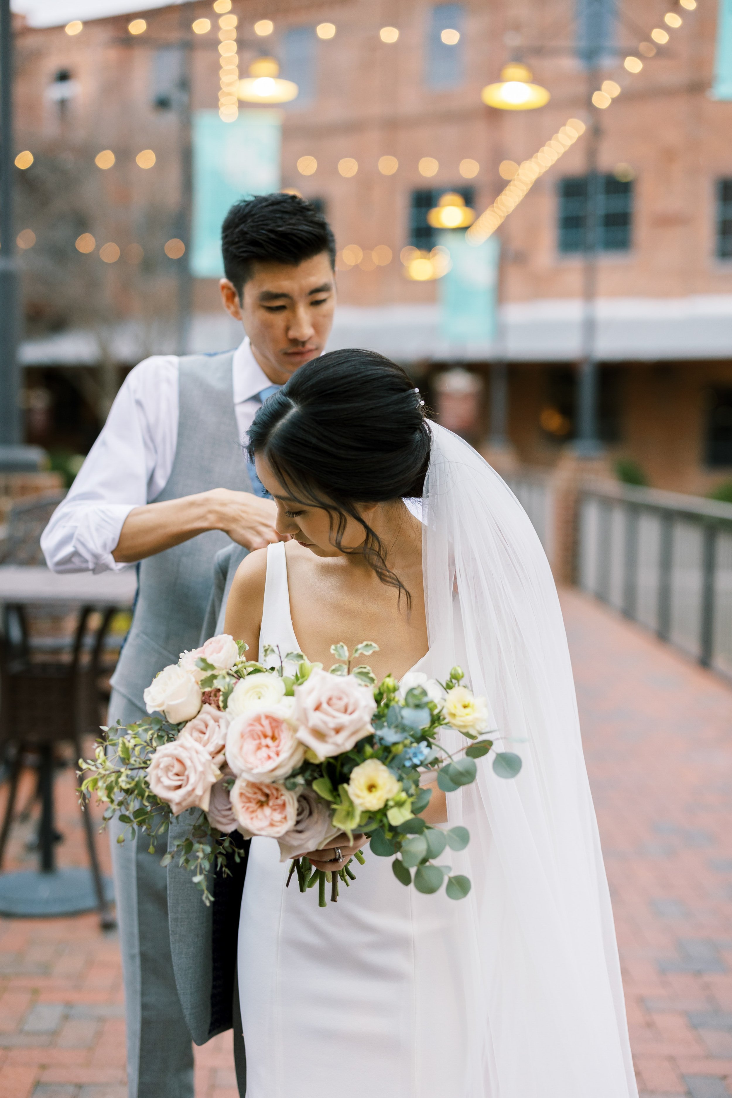 Groom Helps Bride with Veil in American Tobacco Campus Wedding at Bay 7 Durham NC Fancy This Photography