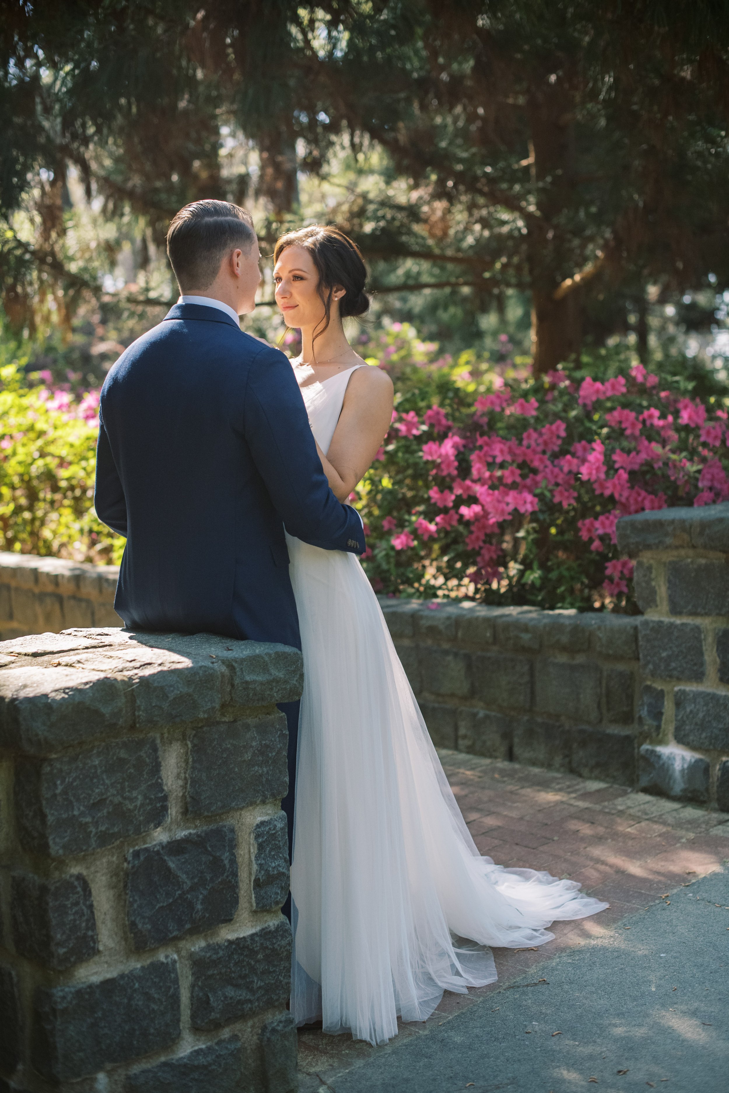 Bride and Groom Golden Hour Sit Stone Wall Cape Fear Botanical Garden Wedding Fancy This Photography