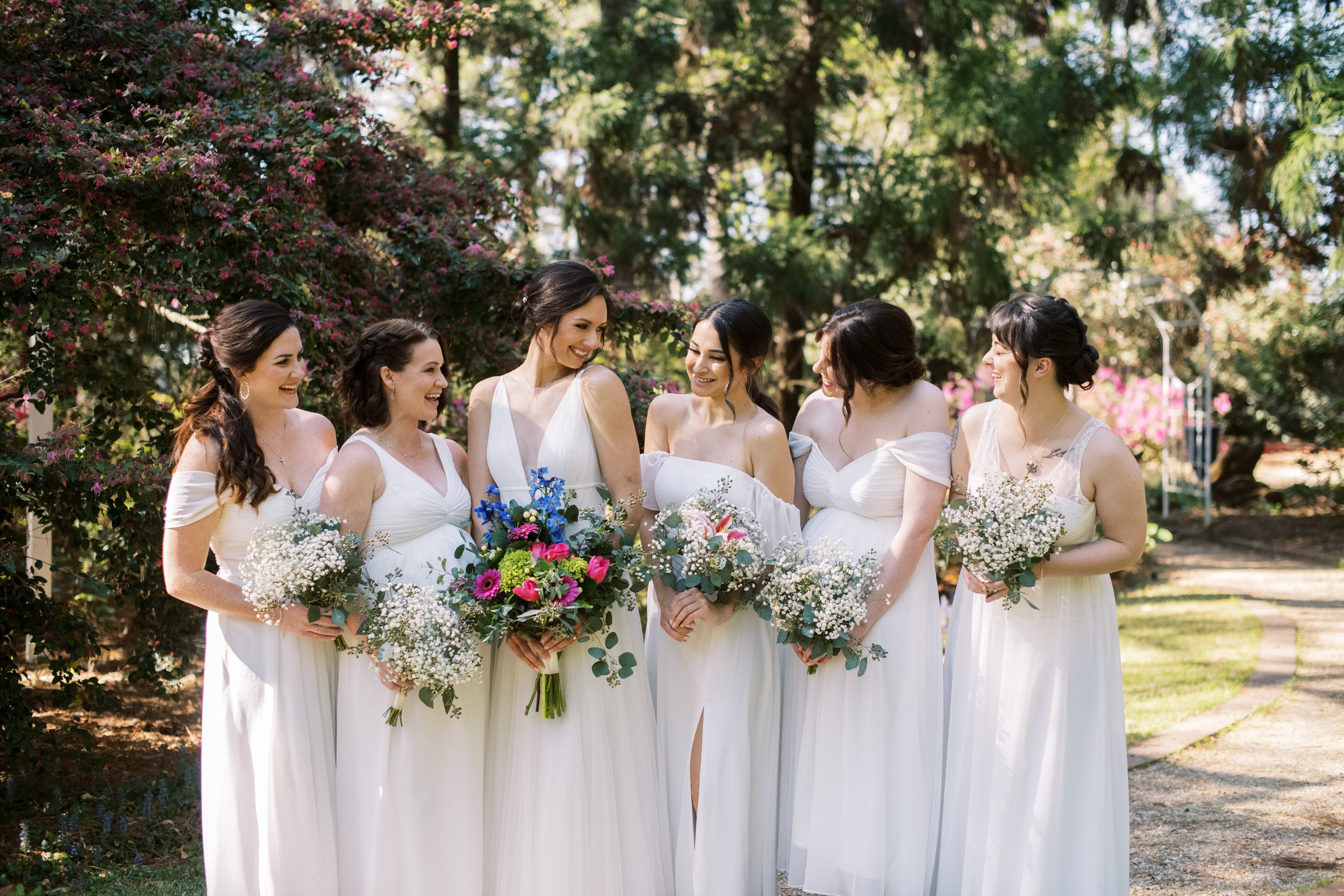 Bridesmaids in White Dresses Smiling with Bride Cape Fear Botanical Garden Wedding Fancy This Photography
