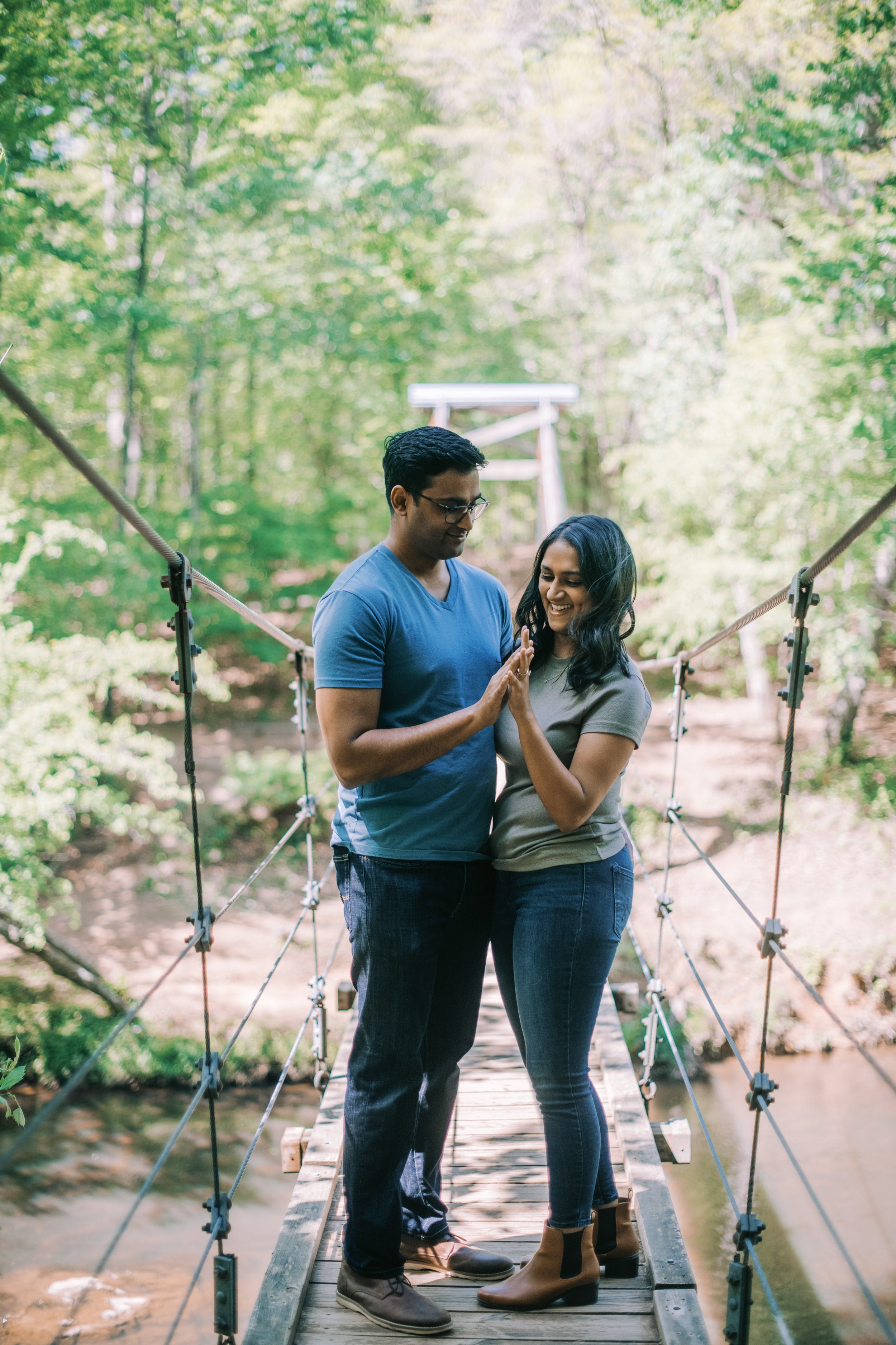 Bride and Groom Hold Hands Swinging Bridge Eno River Engagement Photos Durham NC Fancy This