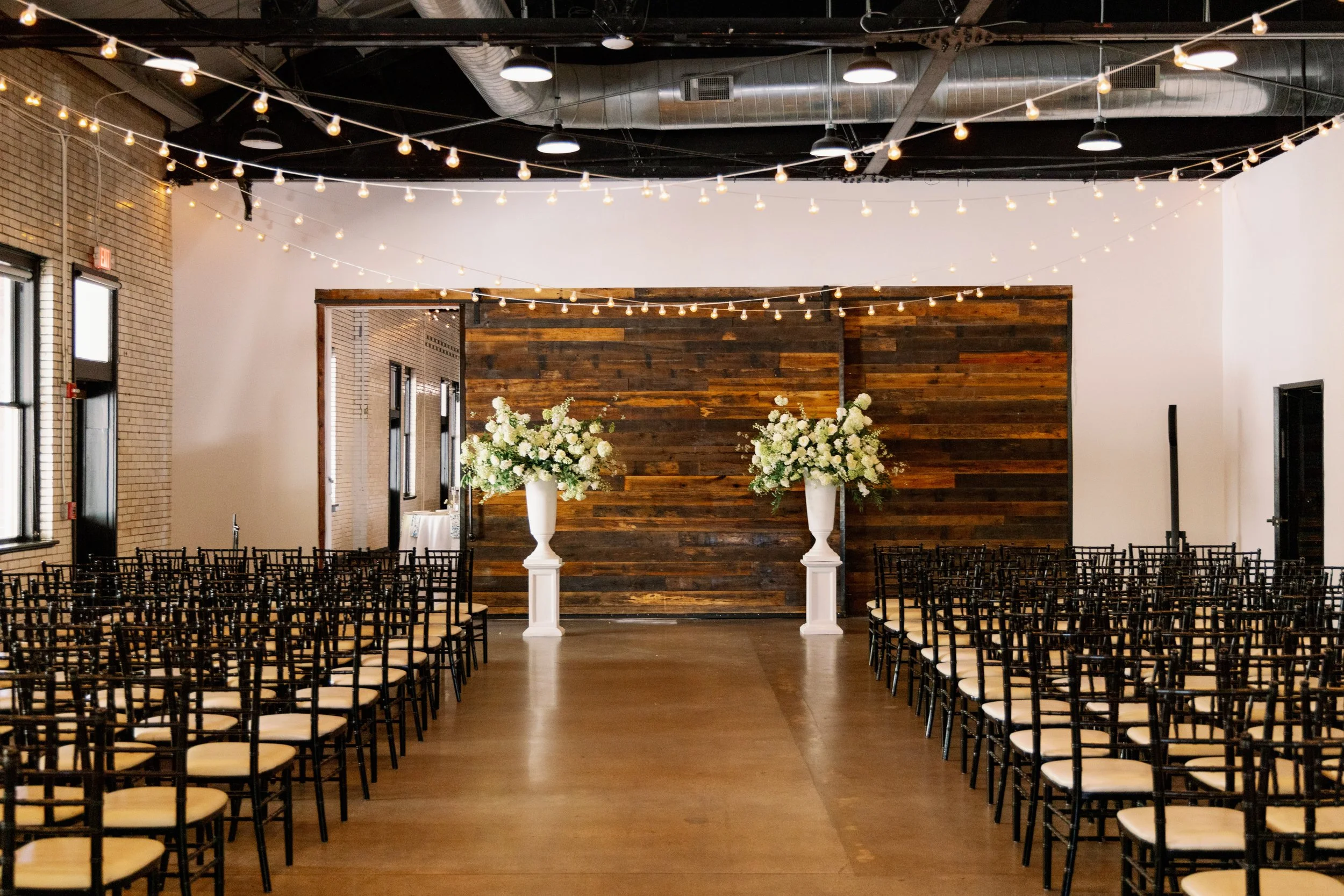 Market Hall wedding ceremony setup with white floral arrangements and string lights in downtown Raleigh