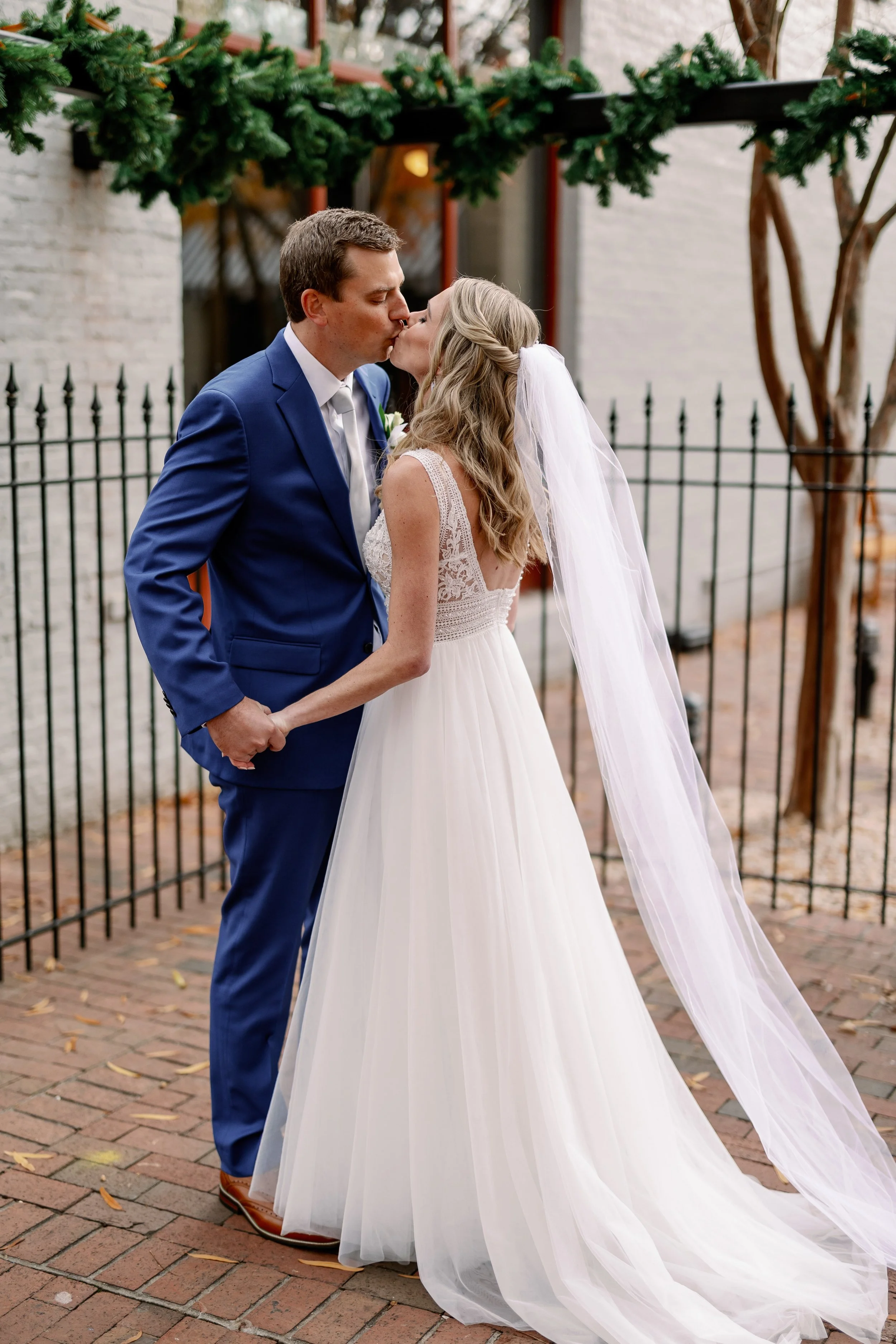 Bride and groom kissing in front of Market Hall during their Raleigh wedding day