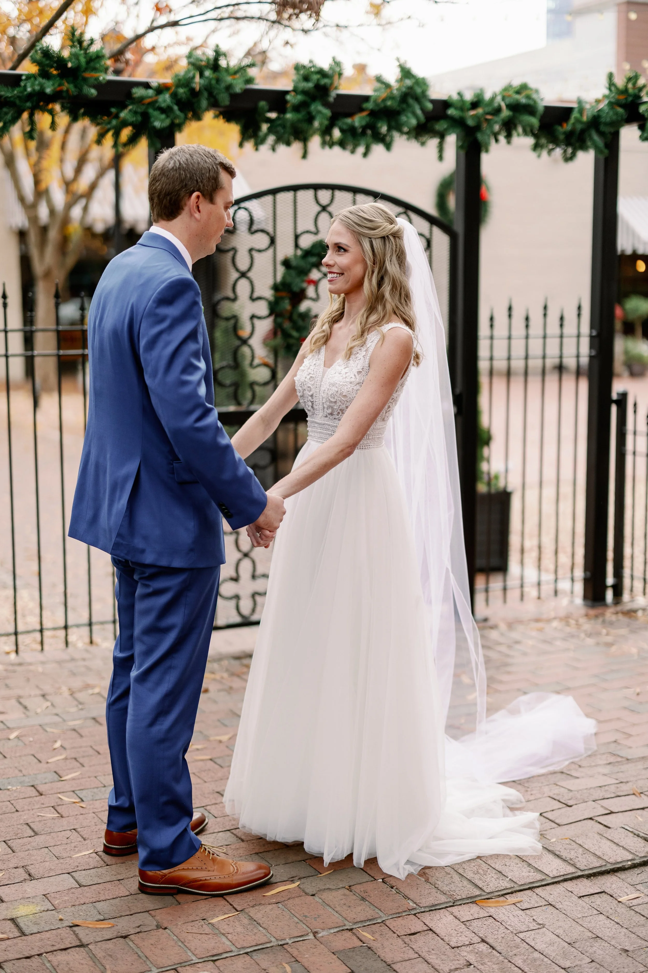 Bride and groom holding hands and smiling during their first look at Market Hall Raleigh