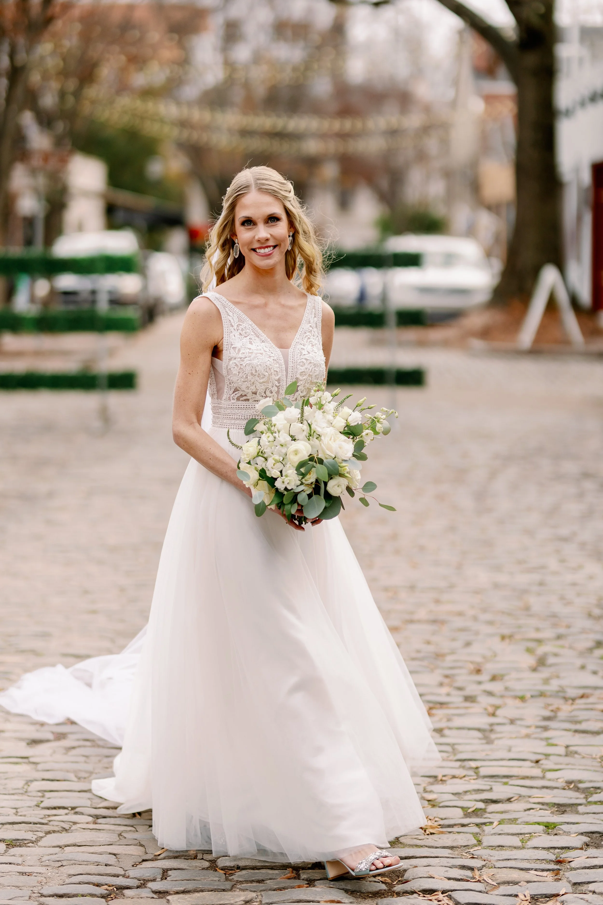 Bride posing on the cobblestone street outside Market Hall with her bouquet