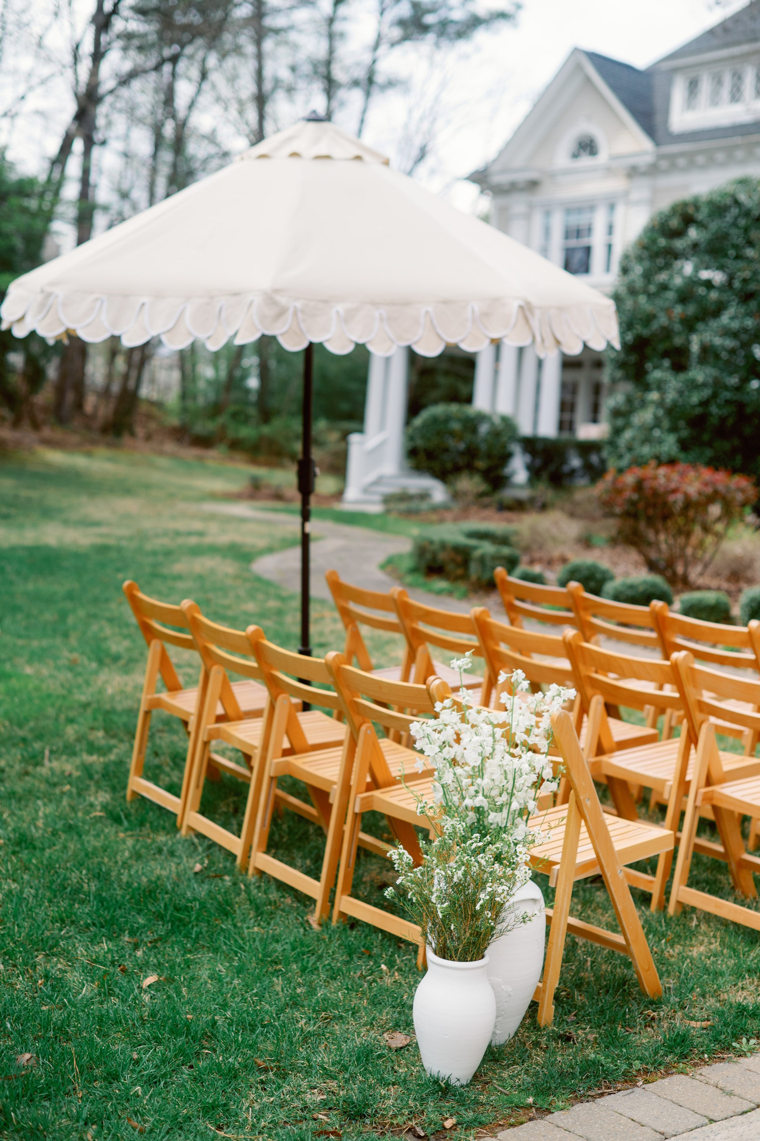 outdoor wedding ceremony setup with chairs and umbrella at McAlister-Leftwich House in Greensboro