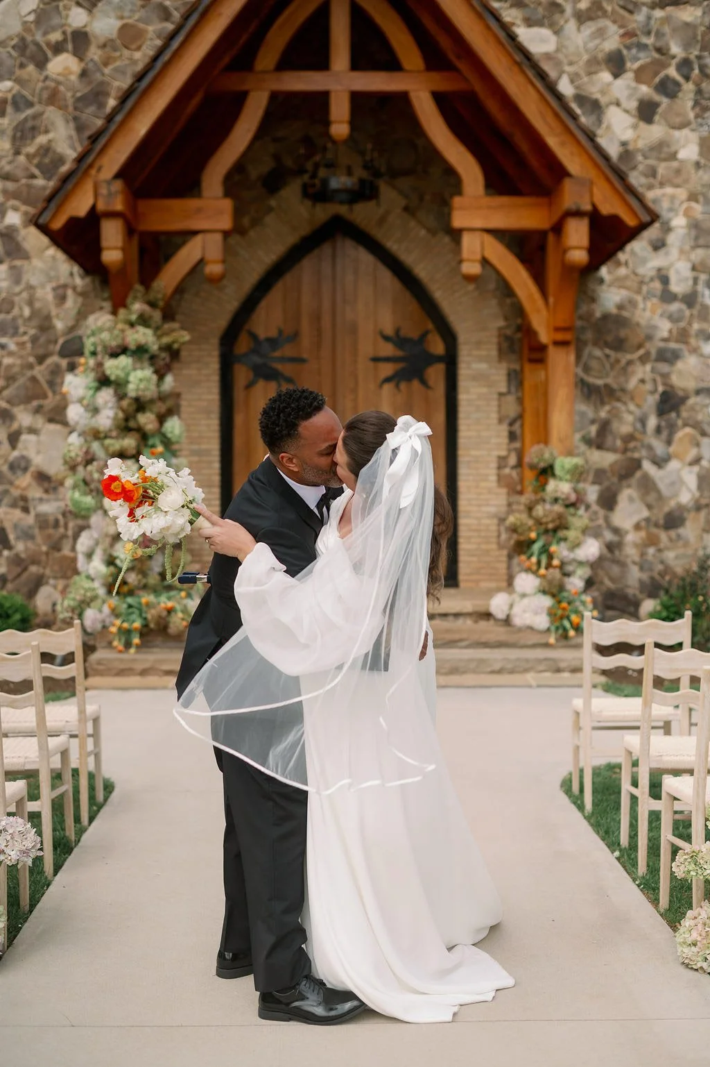 Couple embracing at the arched chapel doors of The Little Chapel at Haven Ridge, Winston-Salem NC wedding 
