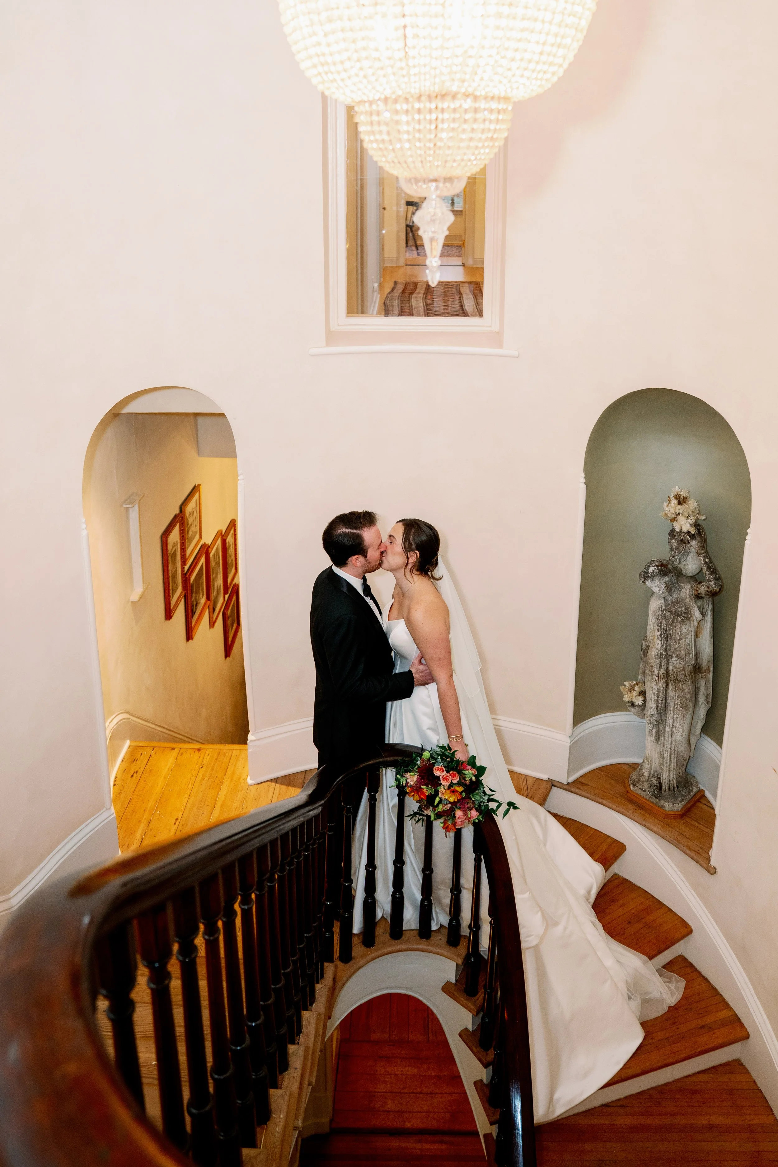  Bride and groom kiss on the rotunda staircase inside Heights House Hotel in downtown Raleigh 