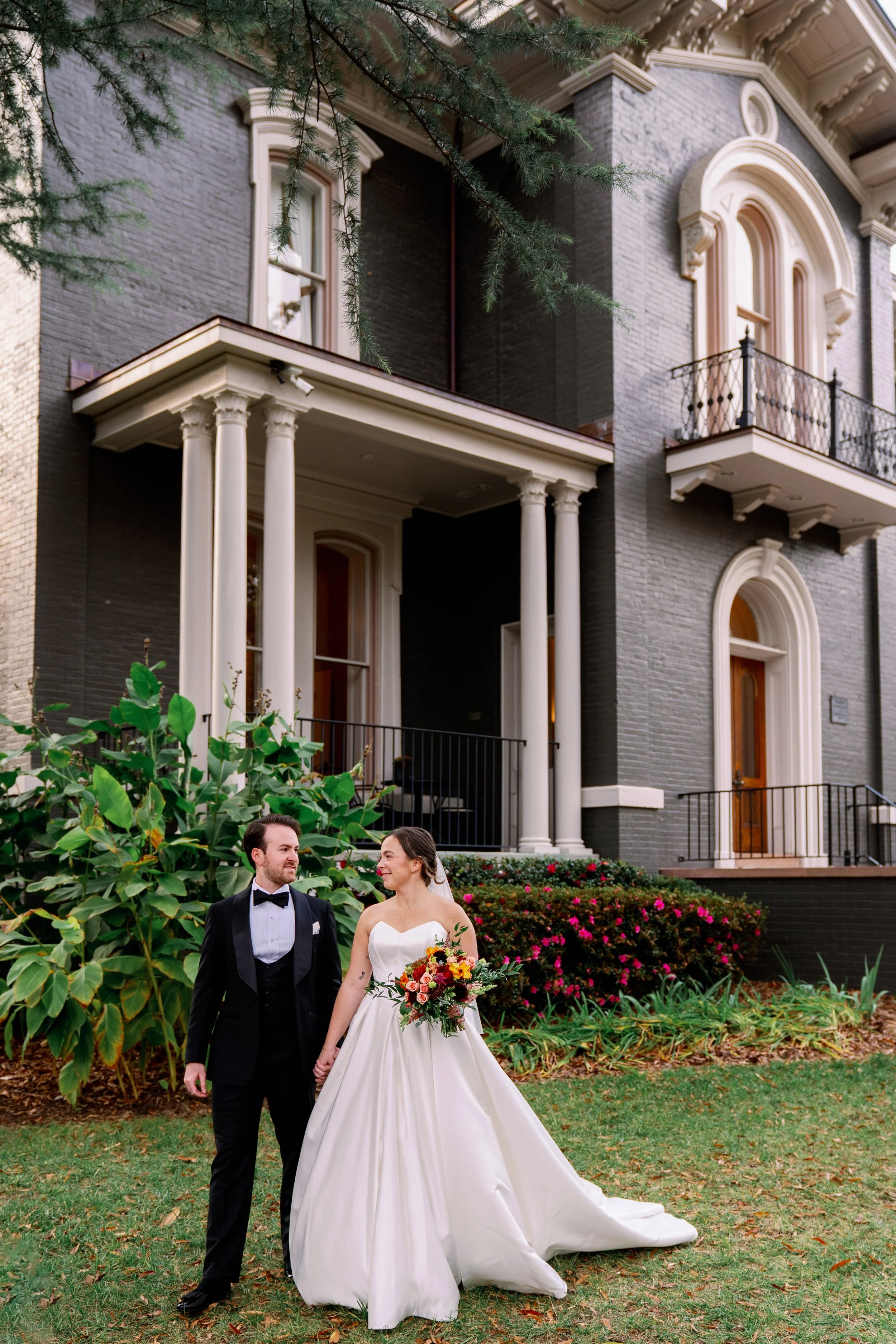  Bride and groom walk hand in hand past the garden and side porch at Heights House Hotel 