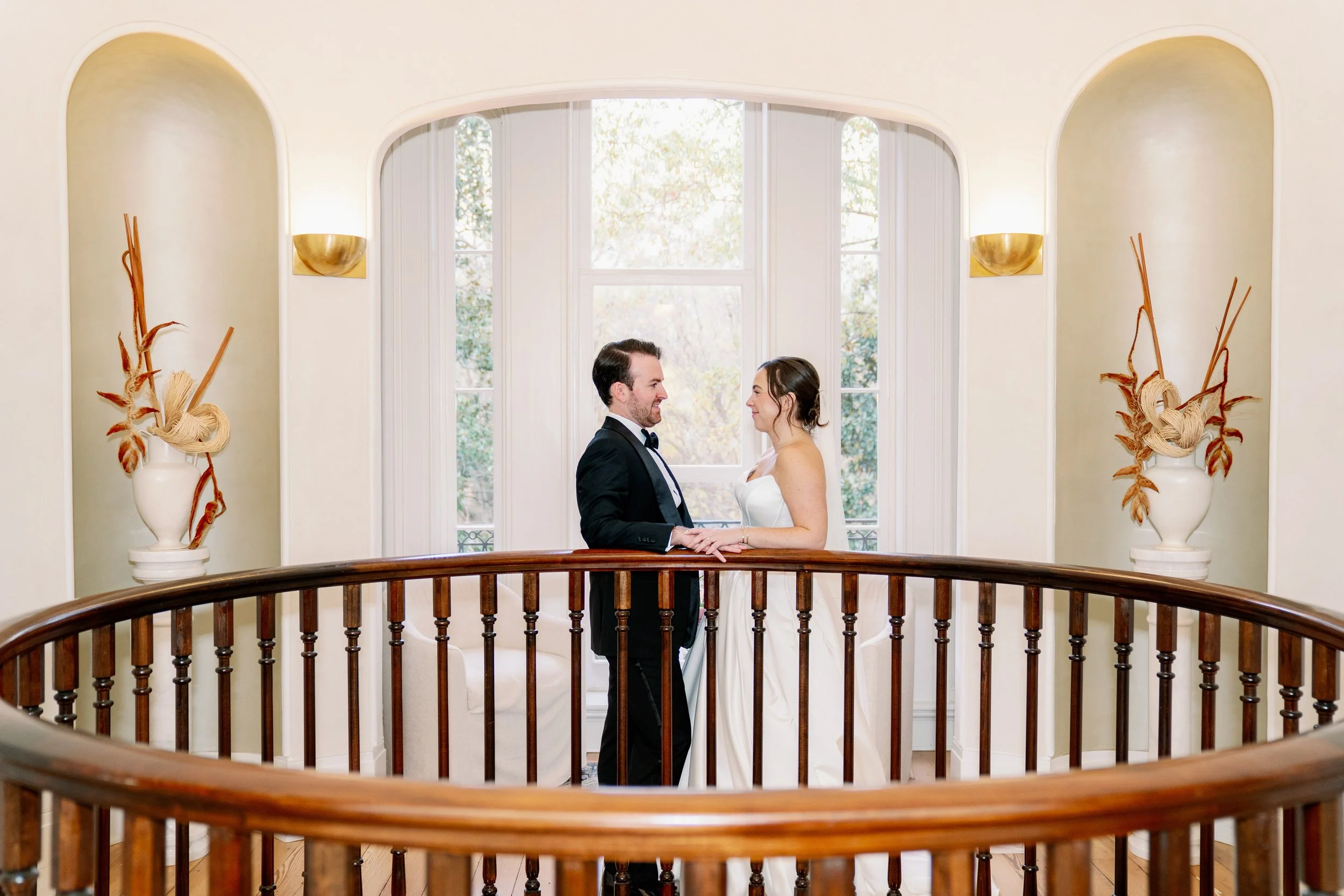 Bride and groom hold hands on the second floor rotunda balcony at Heights House Hotel in Raleigh