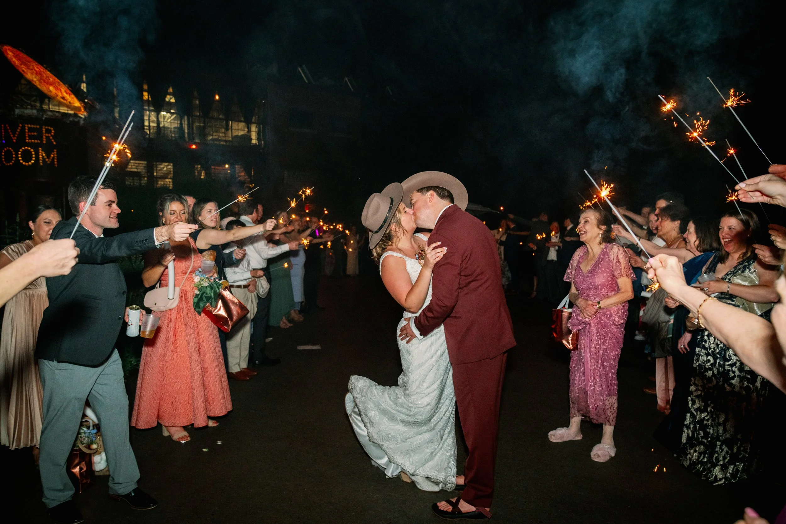 Newlyweds kissing during a sparkler exit at their Haw River Ballroom wedding reception in Saxapahaw, North Carolina at night
