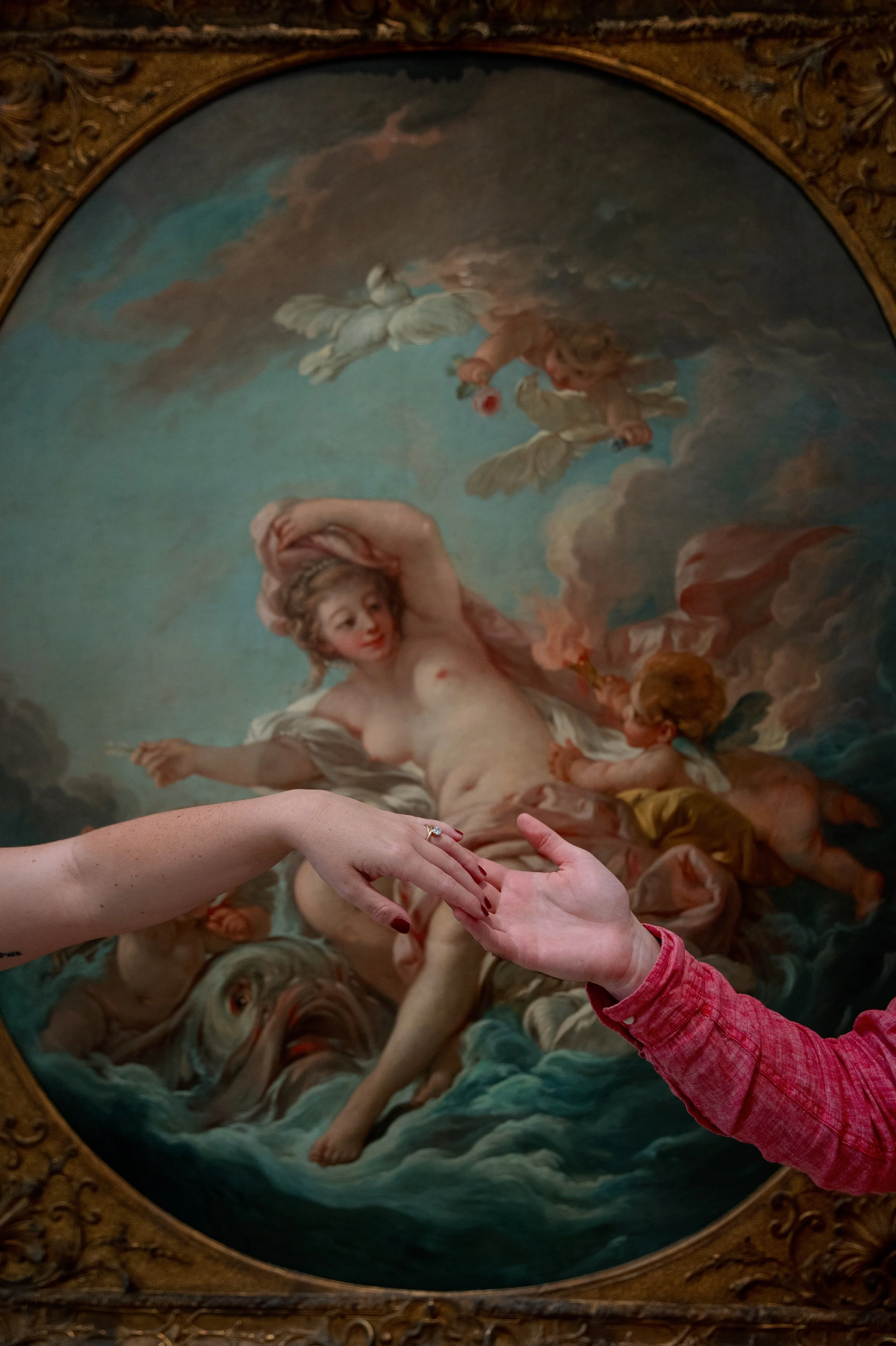 Couple’s hands reaching toward each other in front of a classical painting at the North Carolina Museum of Art, photographed during an NCMA engagement session.