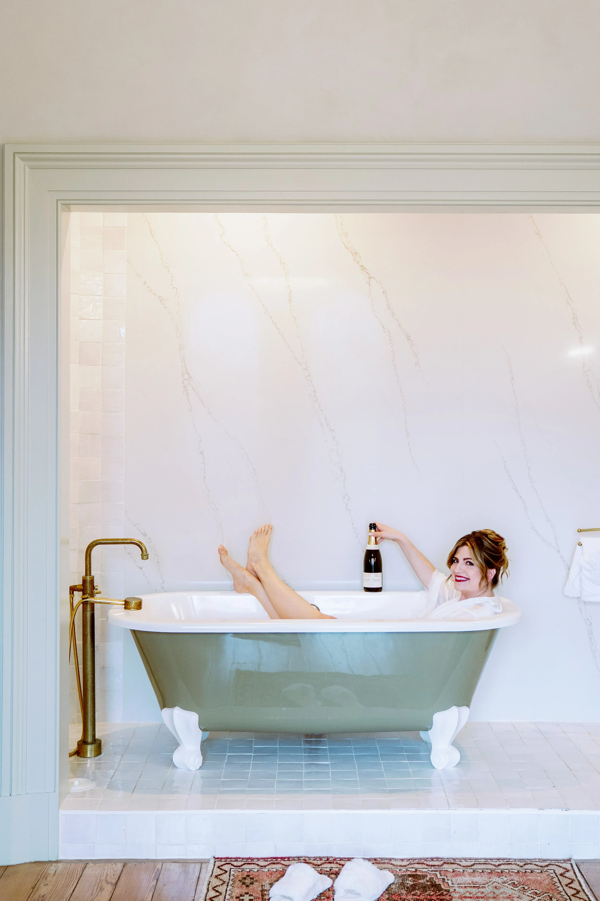 Bride relaxes with champagne in the clawfoot tub inside a Heights House Hotel suite in downtown Raleigh