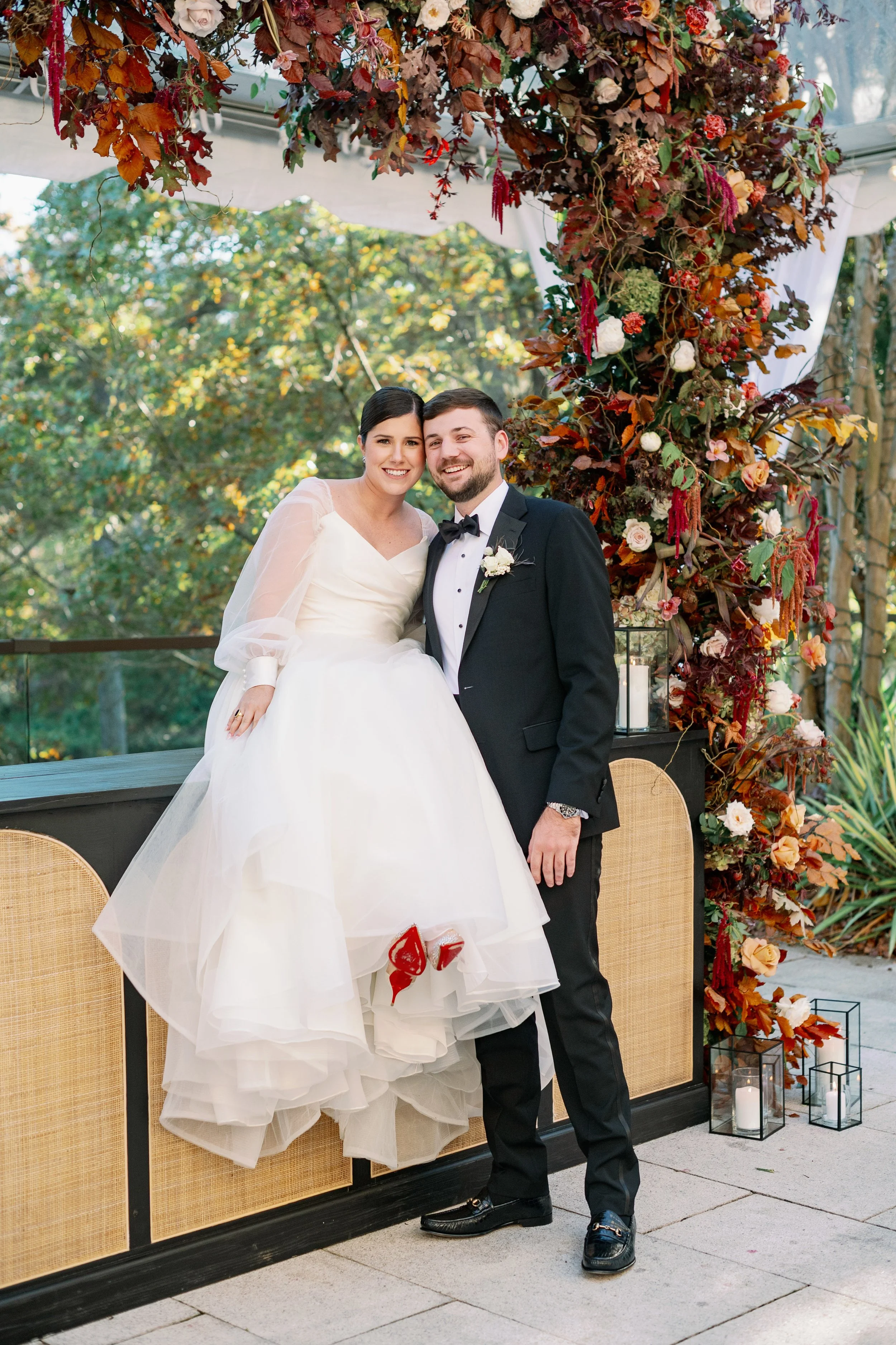 Newlywed couple posing beneath a floral wedding installation at The Umstead Hotel in Cary, NC during an elegant outdoor reception