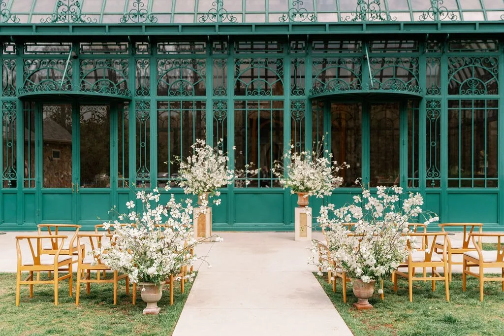Outdoor ceremony setup with dogwood florals against the Solarium glass at The Little Chapel at Haven Ridge, Winston-Salem
