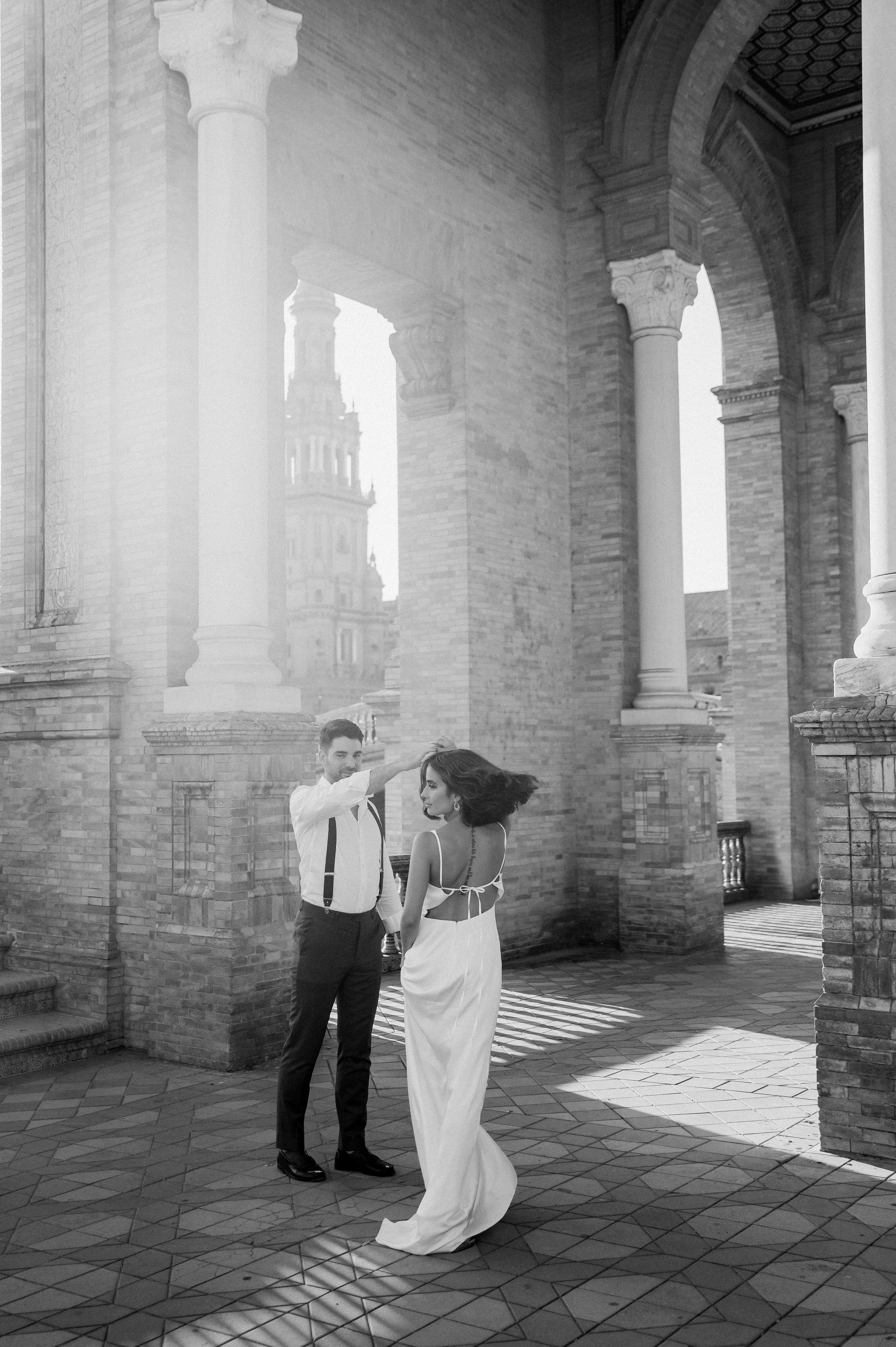 An intimate black-and-white moment of a couple dancing beneath the arches of Plaza de España in Seville. The sweeping architecture, soft light, and natural movement capture the romance of Spain while keeping the focus on connection and emotion. This 