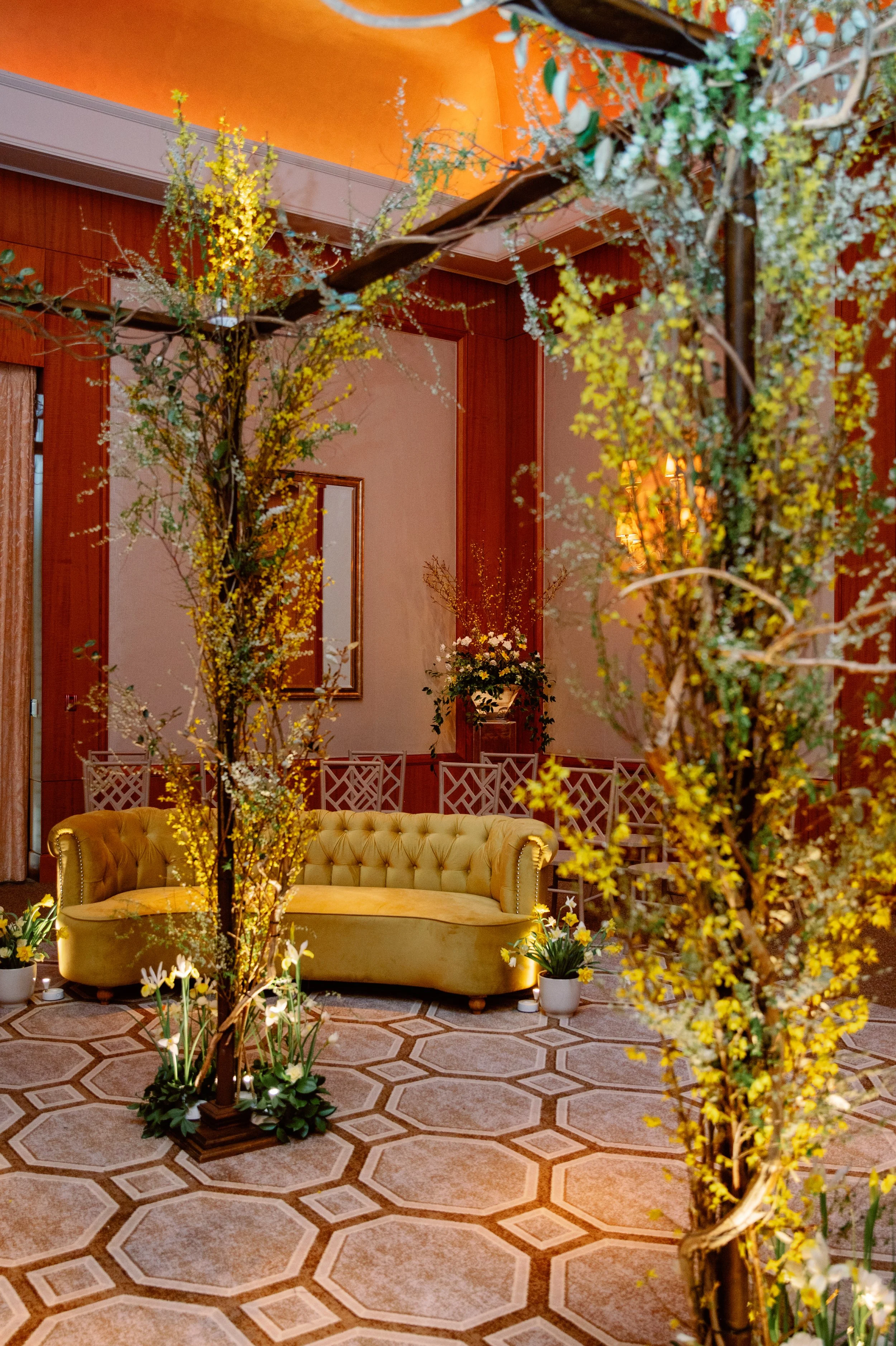 Elegant indoor wedding lounge at The Umstead Hotel in Cary, North Carolina featuring floral installations, a velvet sofa, and warm ambient lighting