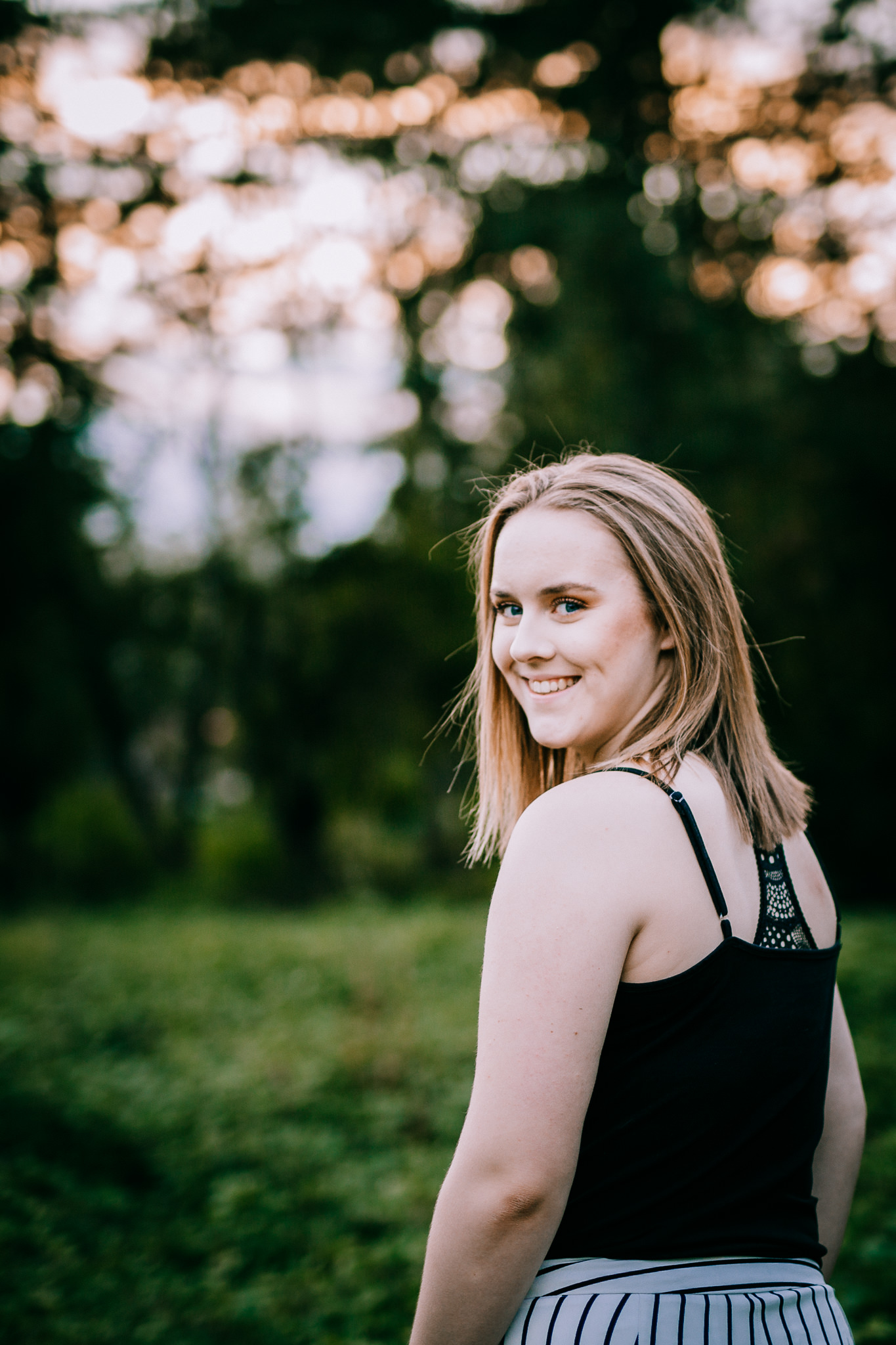 Chilliwack teenager standing in field with sunsetting behind her. 