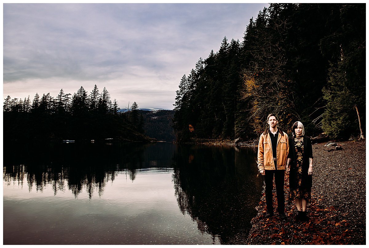  Couple standing on beach staring at photographer during their engagement session on the beach at Harrison Hot Springs. 